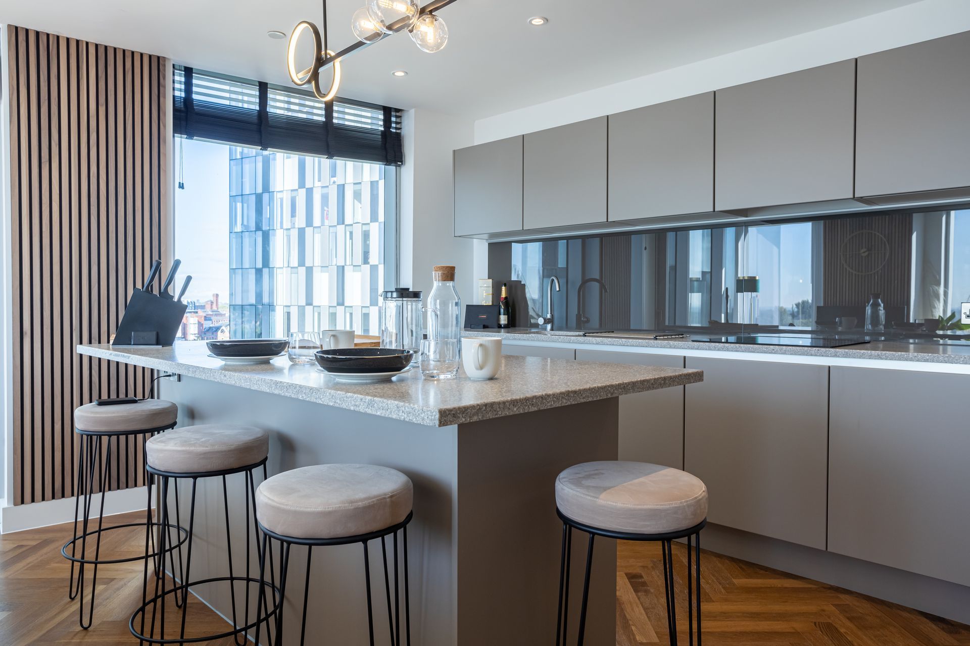 Modern kitchen with gray cabinets, island with stools, and large window.