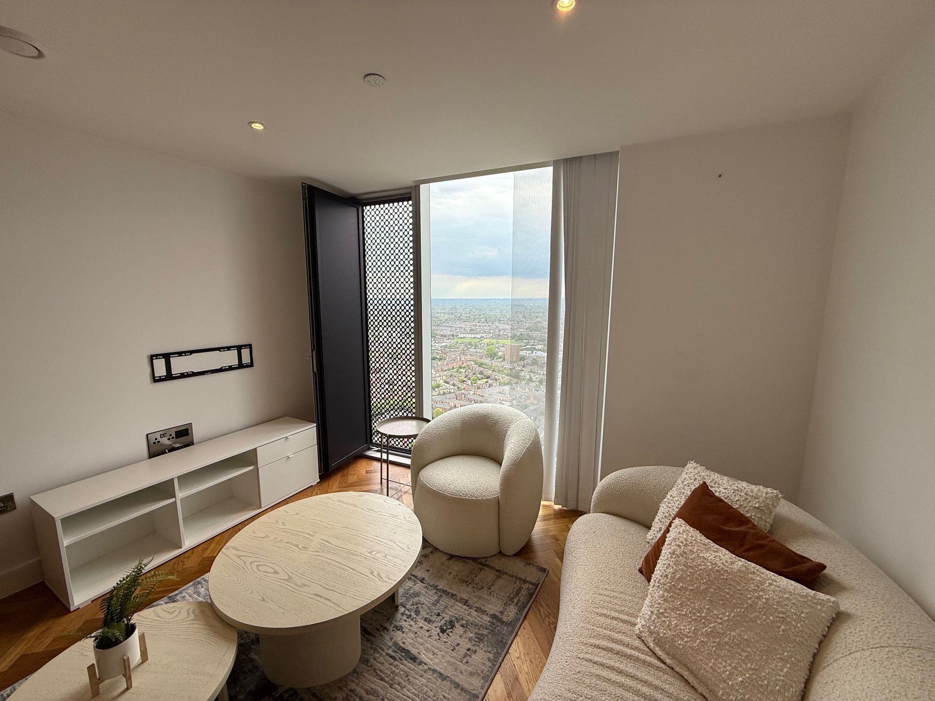 Modern living room with a city view, white furniture, and a round coffee table.