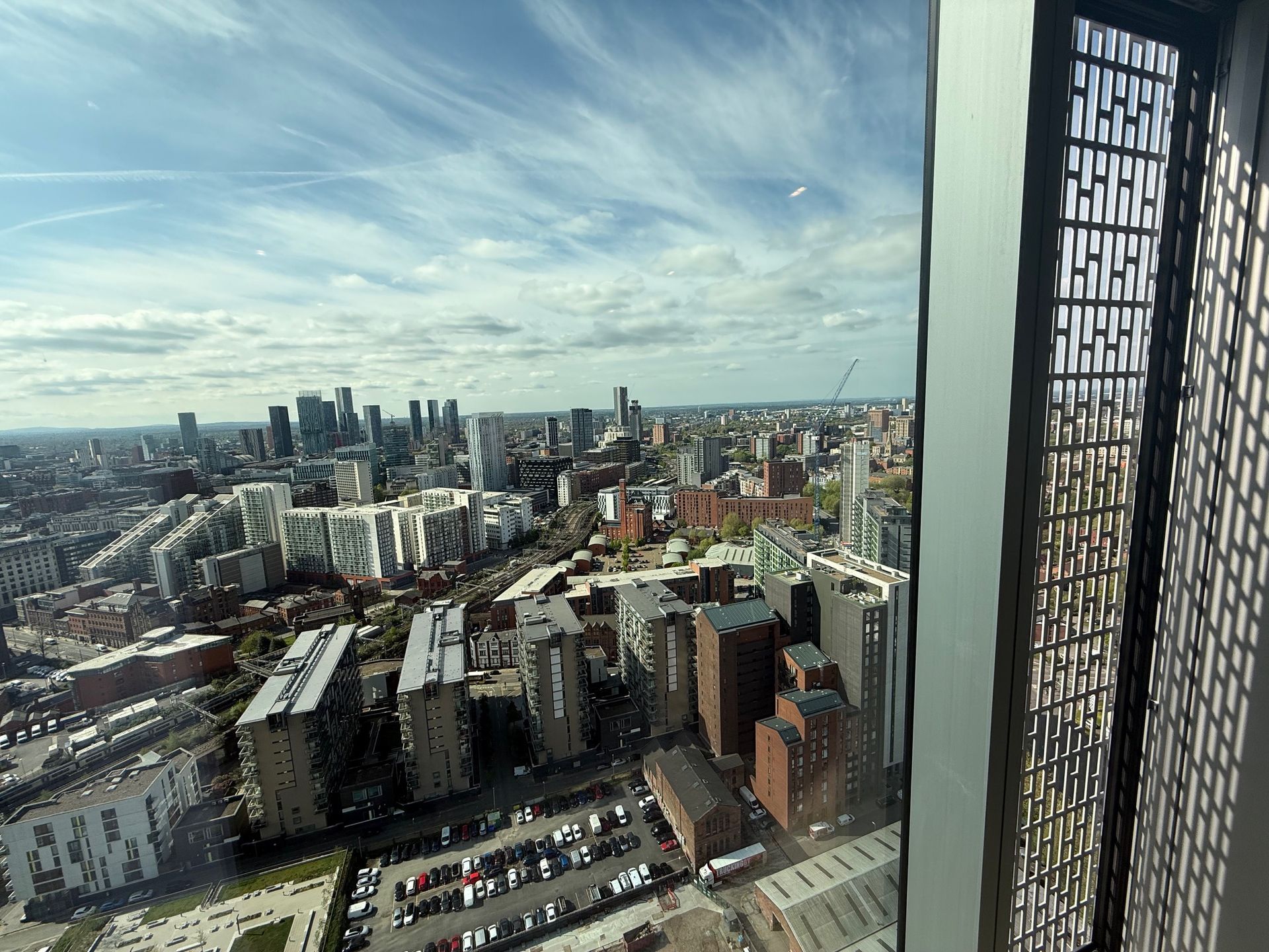 Cityscape view from a tall building window, with skyscrapers, blue sky, and a decorative architectural panel.