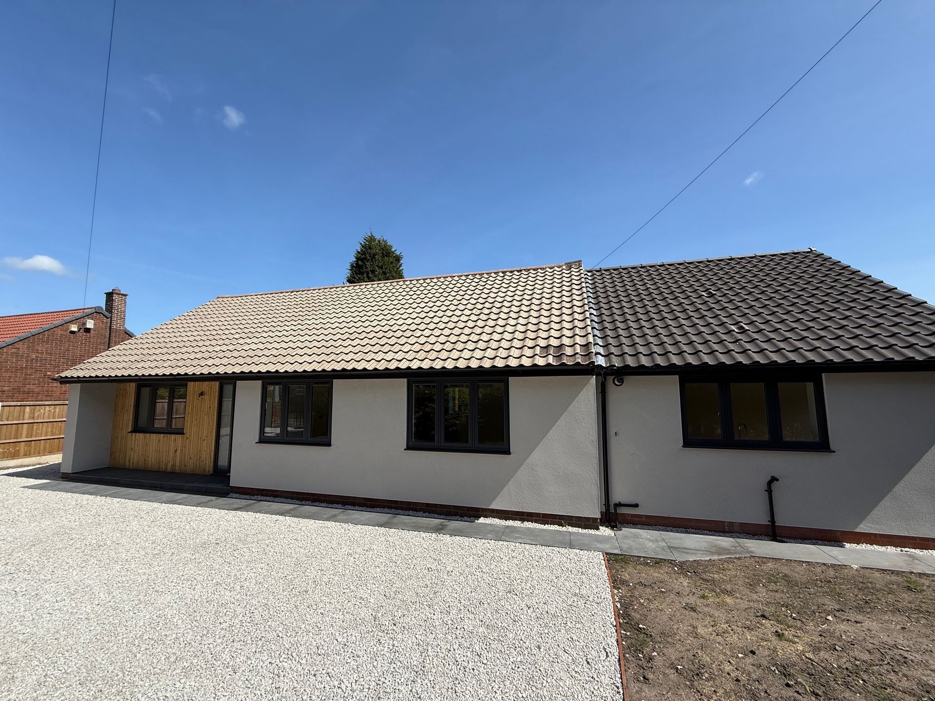 Exterior of a bungalow with new roof tiles and gravel driveway.