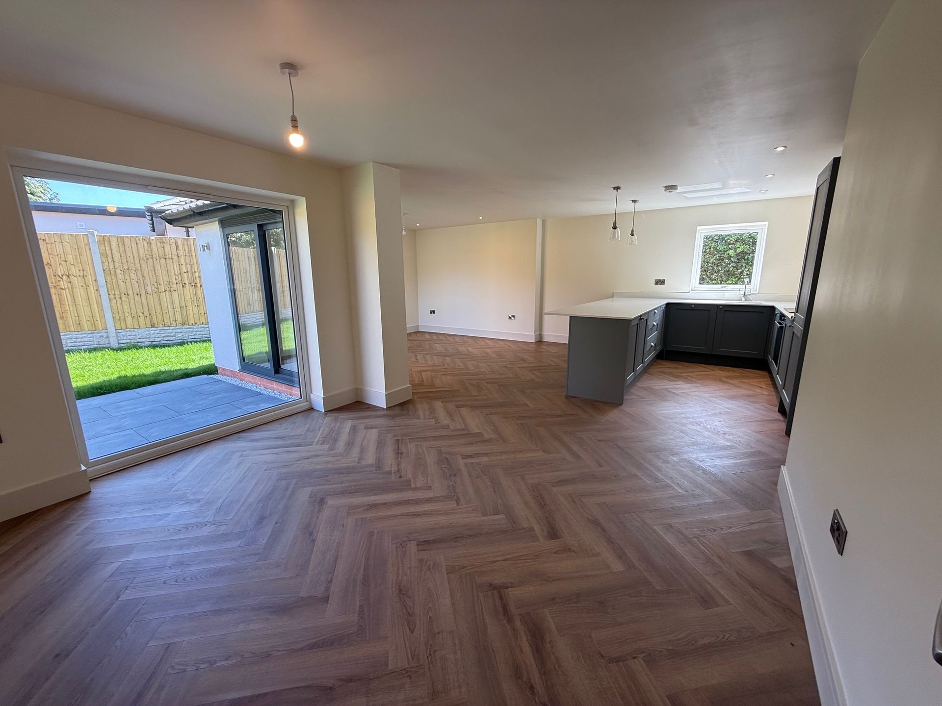 Open-plan kitchen with wood flooring, island, cabinets, and sliding door to patio.