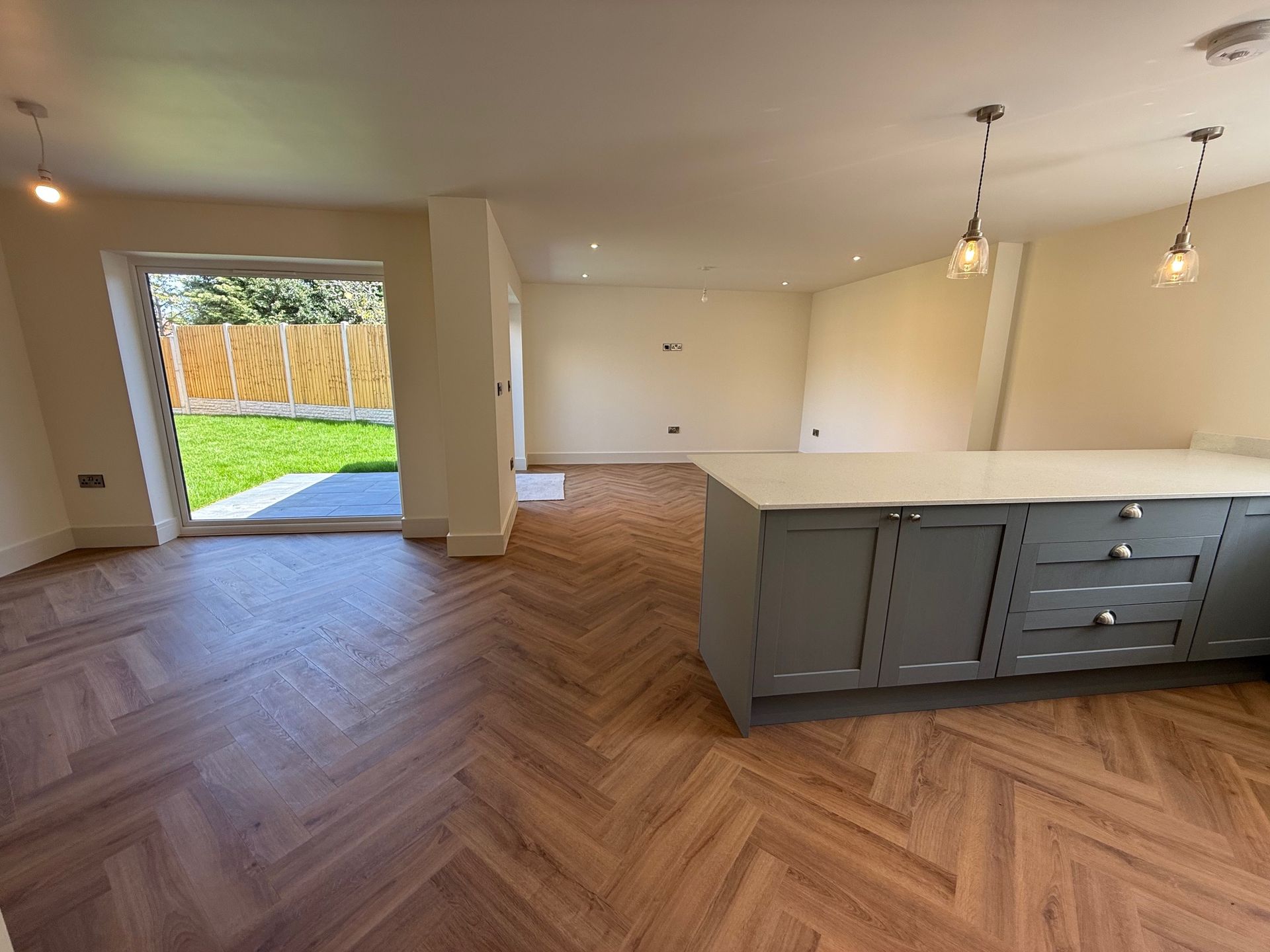 Kitchen interior with wood flooring, grey island, and a door leading to a yard.