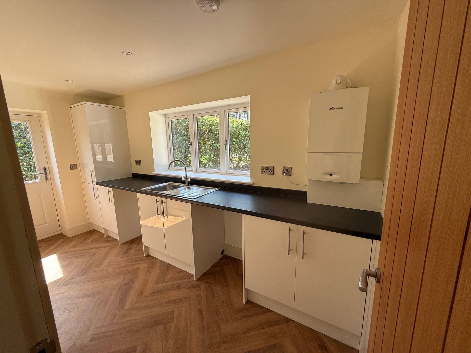 Modern kitchen with white cabinets, dark countertop, and wood-patterned floor.