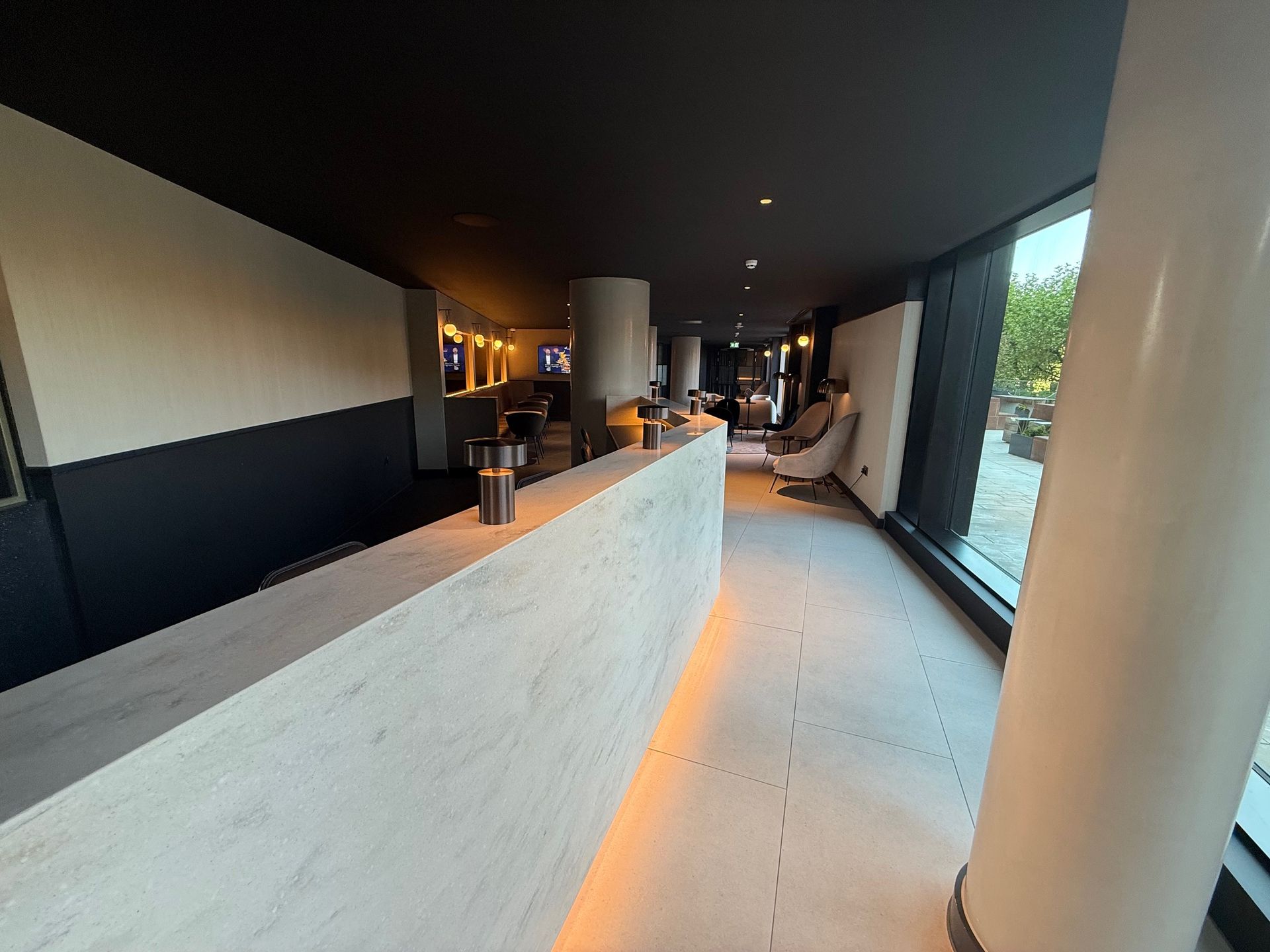 Modern hallway with a curved counter, large windows, and a black and white wall.