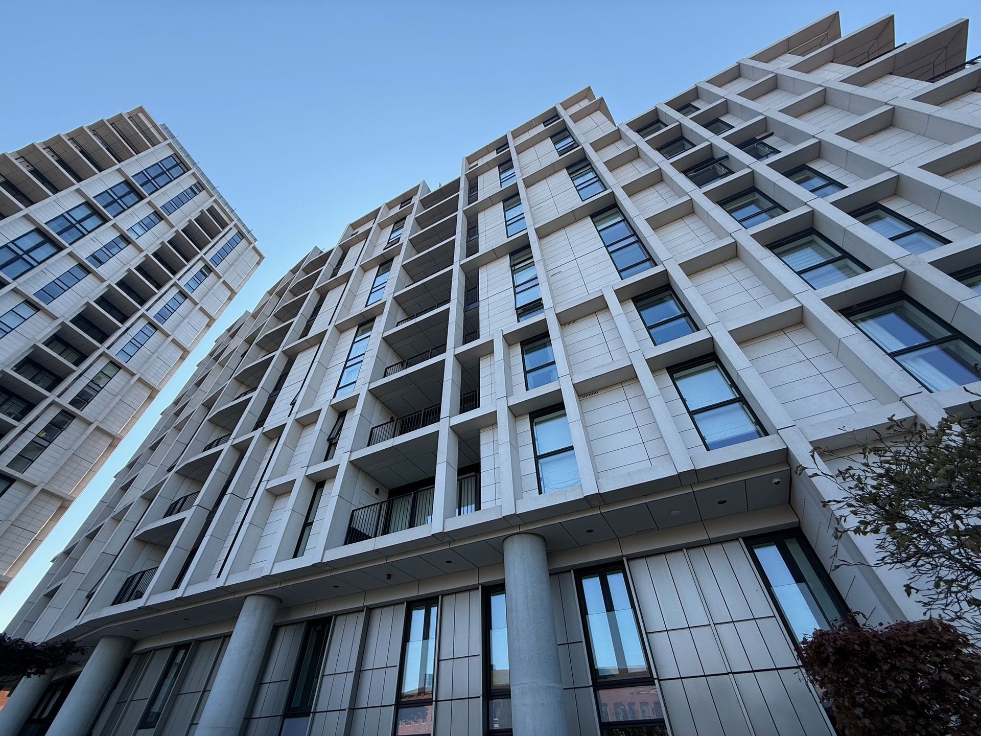 Modern high-rise apartment buildings with white facade against a blue sky.