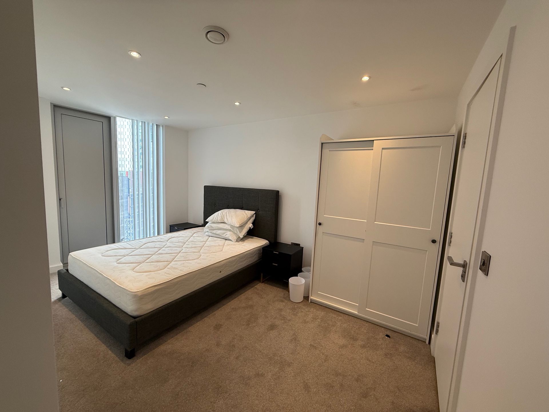 Bedroom with a bed, wardrobe, and door. Neutral tones and ambient lighting.