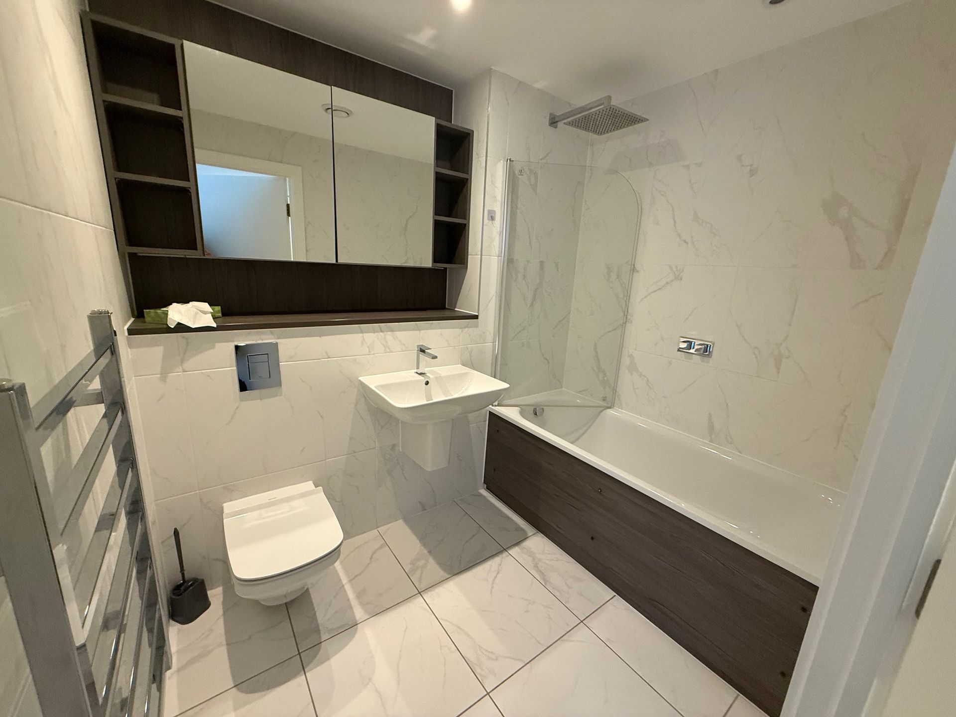 Modern bathroom with white and wood accents; includes a toilet, sink, bathtub, and shower.