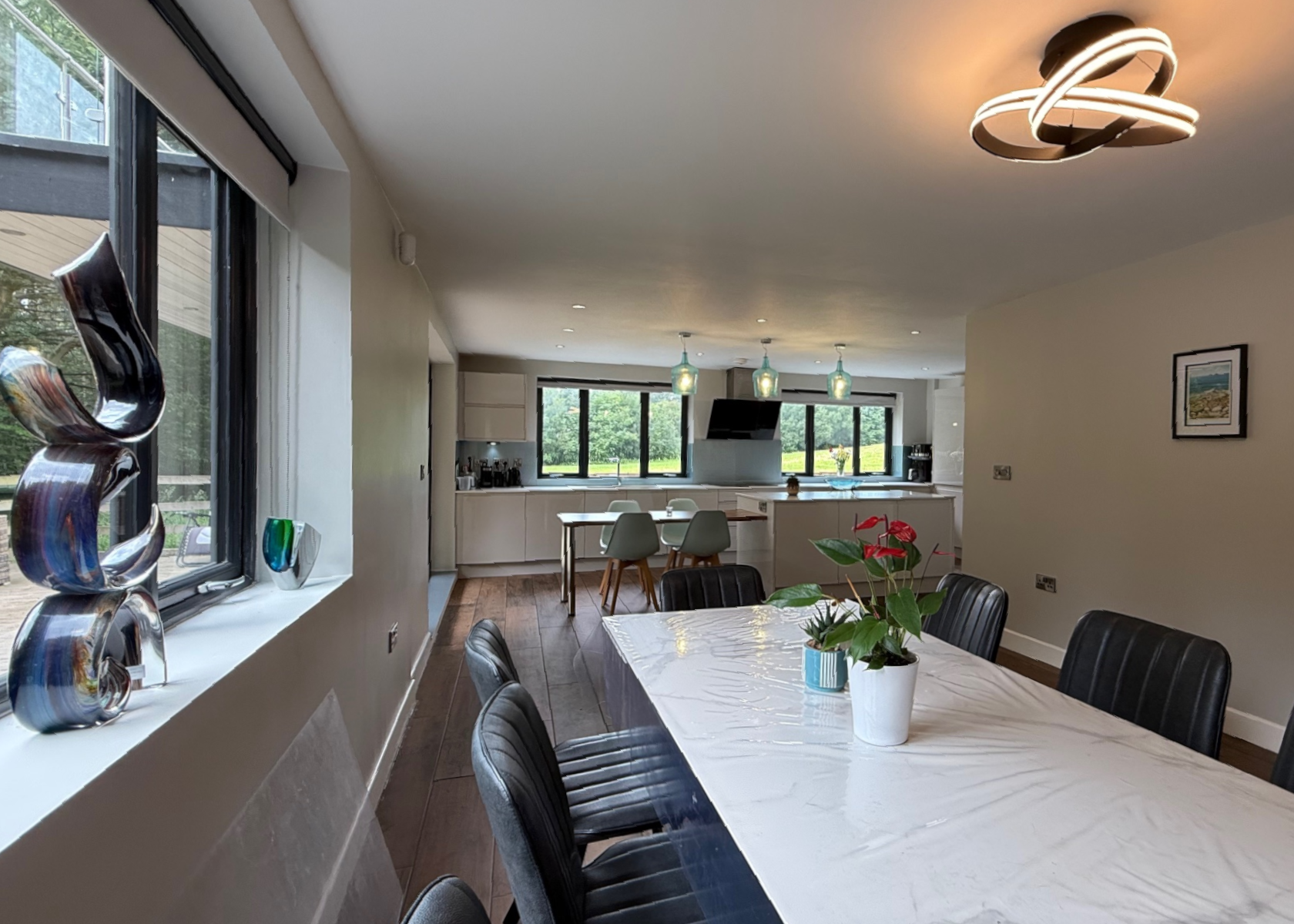 Dining area with a long table, chairs, and view to kitchen.
