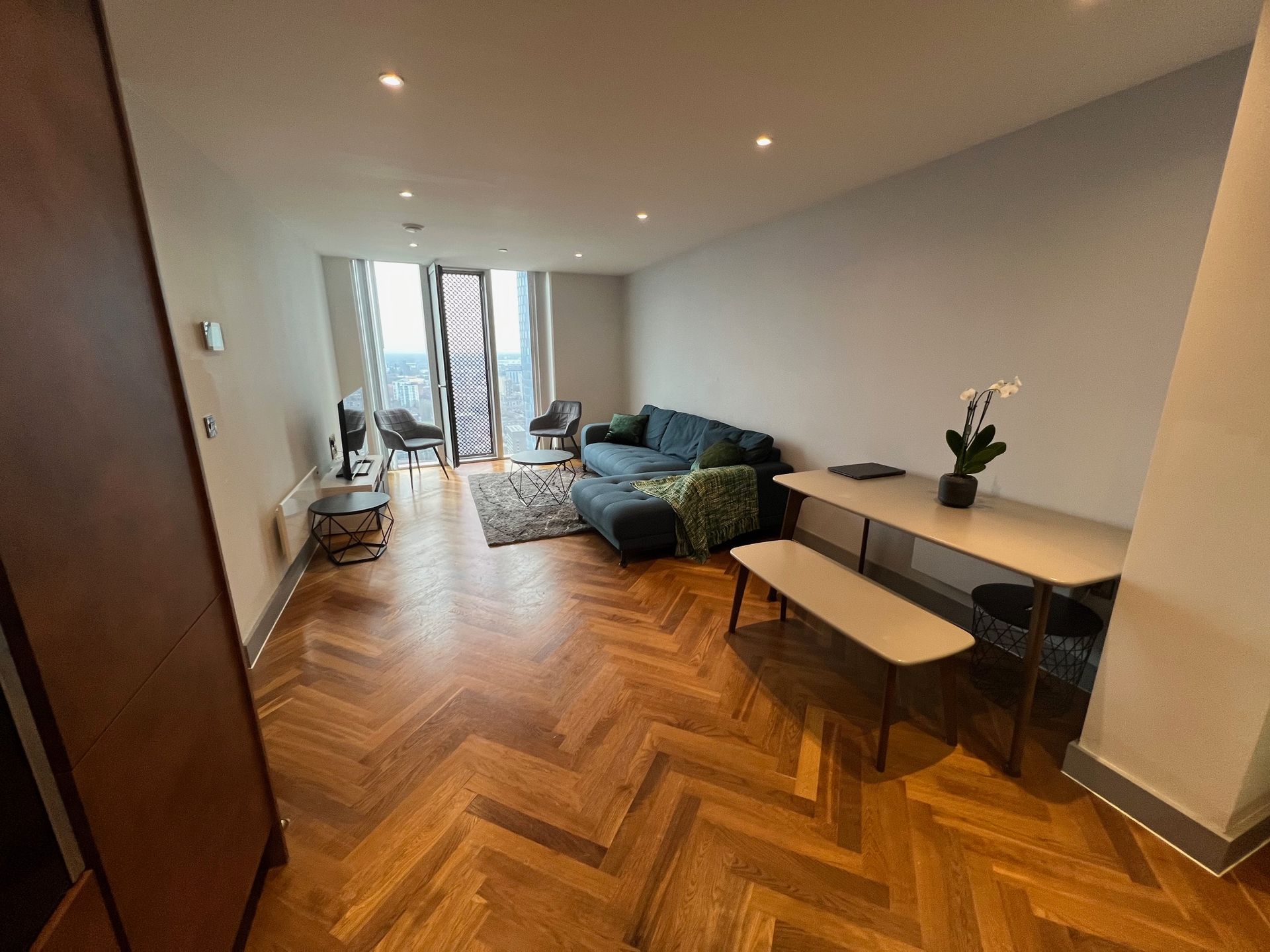 Living room with blue sofa, wooden dining set, and hardwood floors.