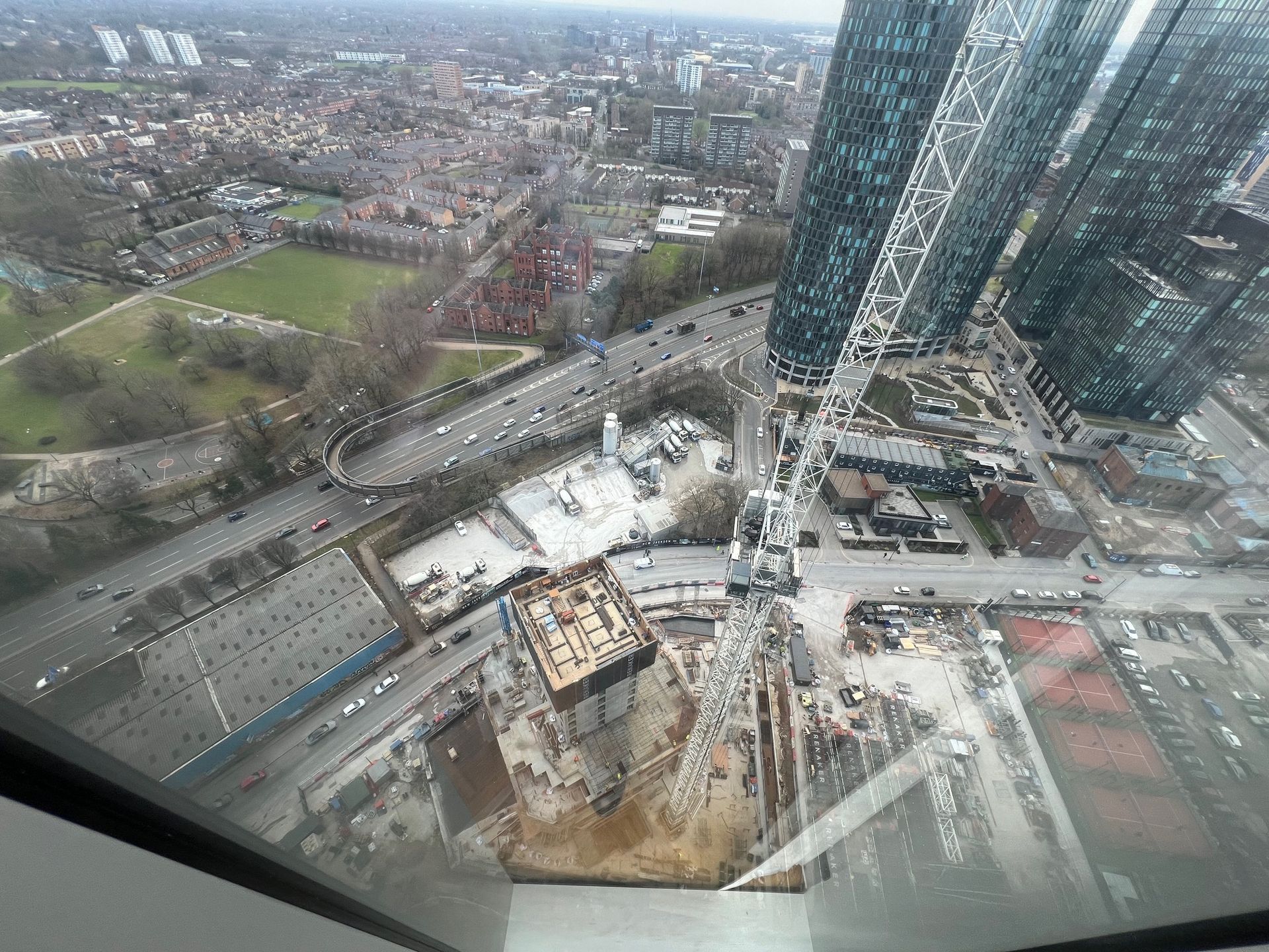 High-angle view of a city with tall buildings, a highway, and a construction site.