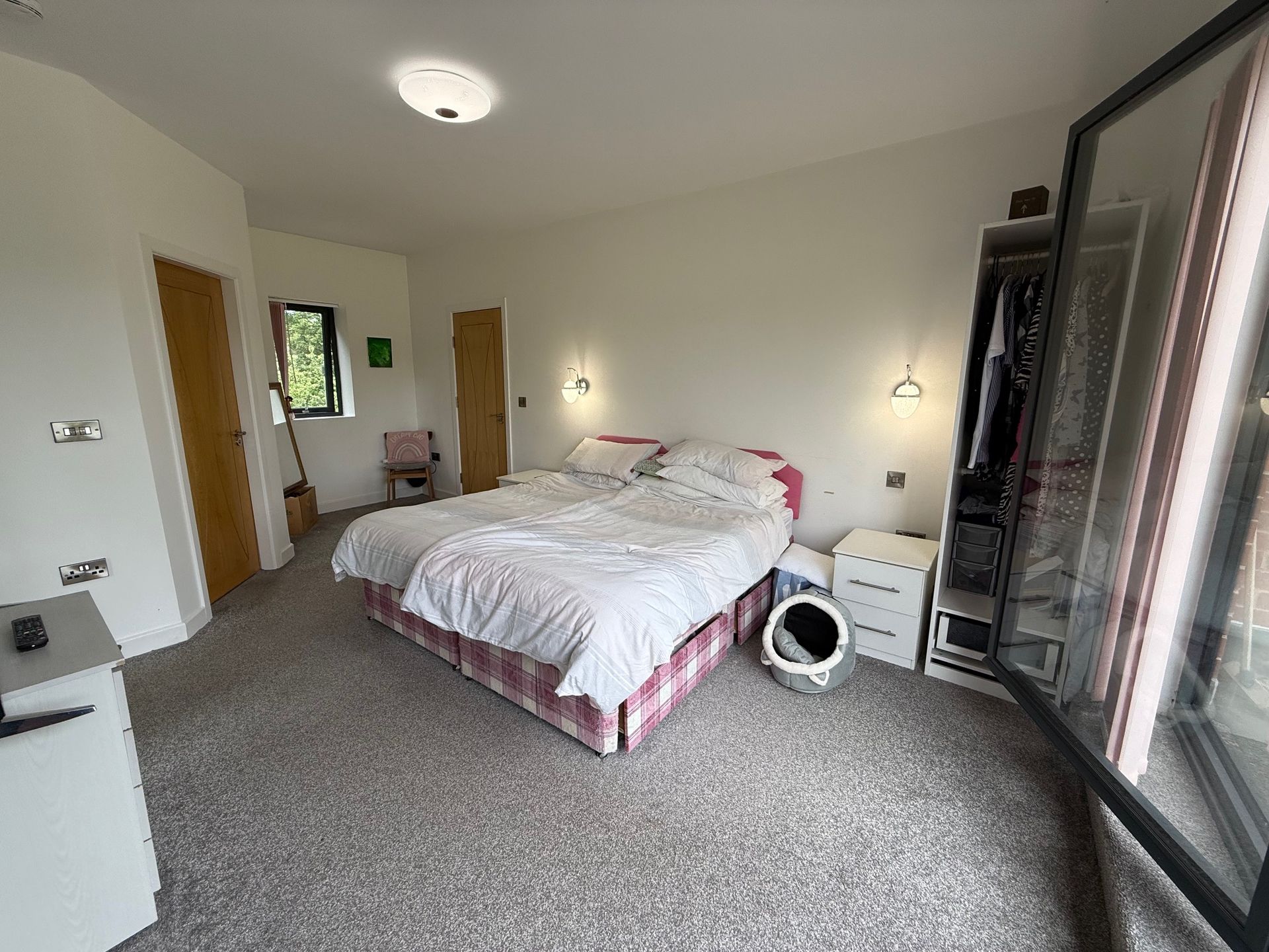 Bedroom with bed, closet, and window. Pink bed frame, neutral walls, and light-colored carpet.