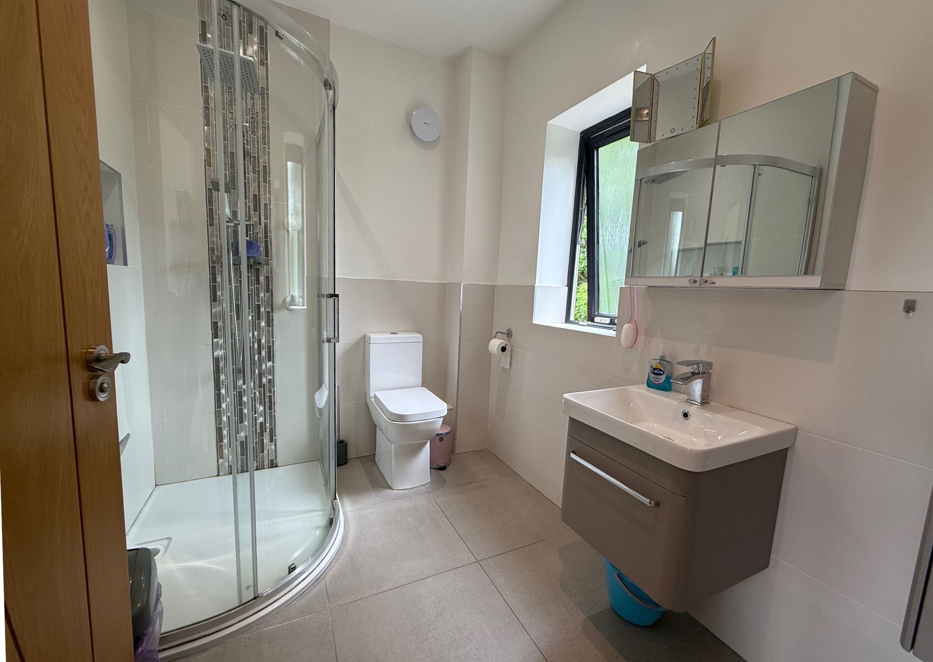 Bathroom with a shower, toilet, sink, and storage cabinets.