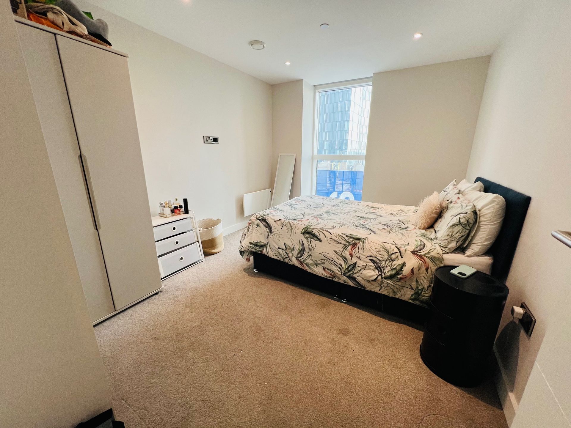 Bedroom with bed, wardrobe, and dresser; neutral colors.
