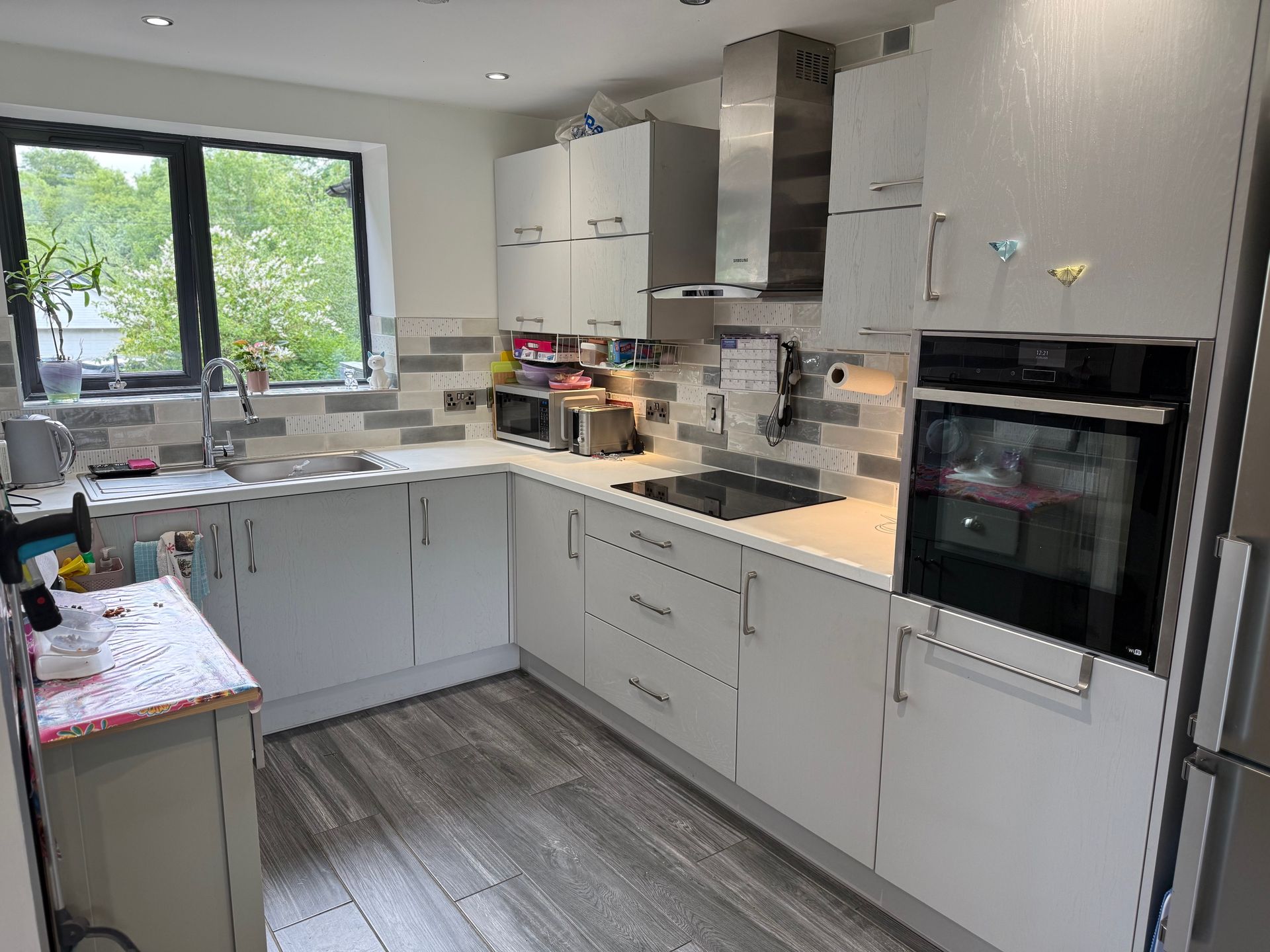 A modern white kitchen with cabinetry, stainless steel appliances, and a gray-tiled backsplash.