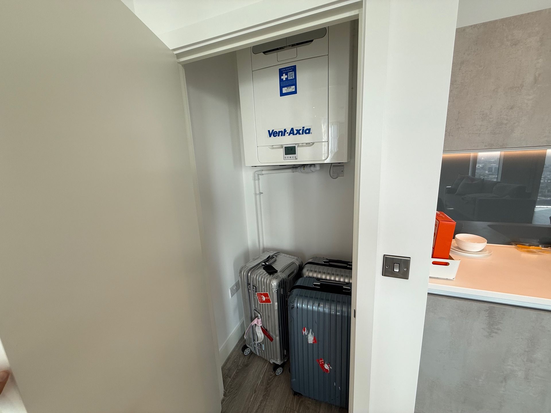A small closet with a water heater and two suitcases. The door is ajar.
