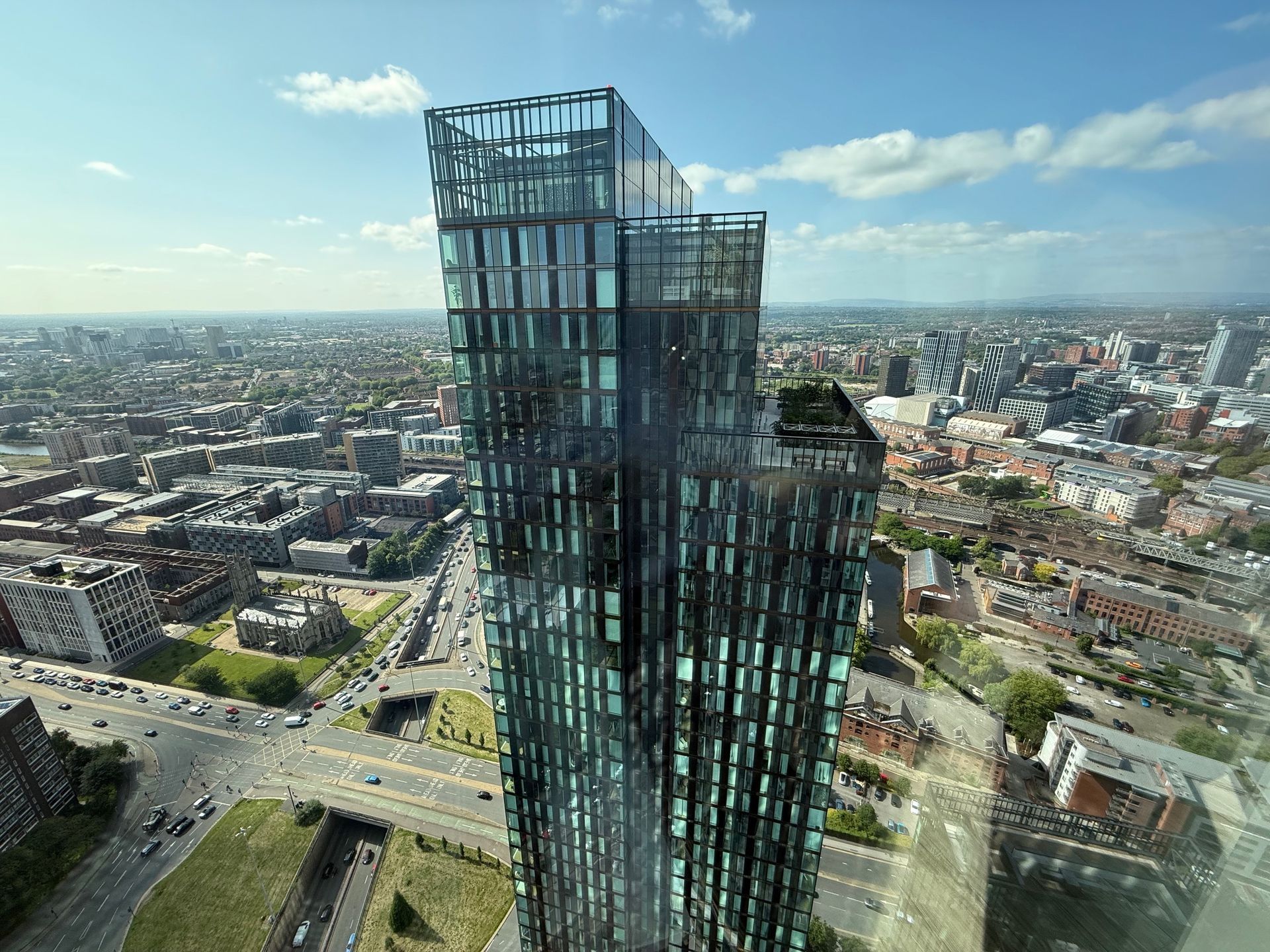 Modern glass skyscraper against a city skyline on a sunny day.