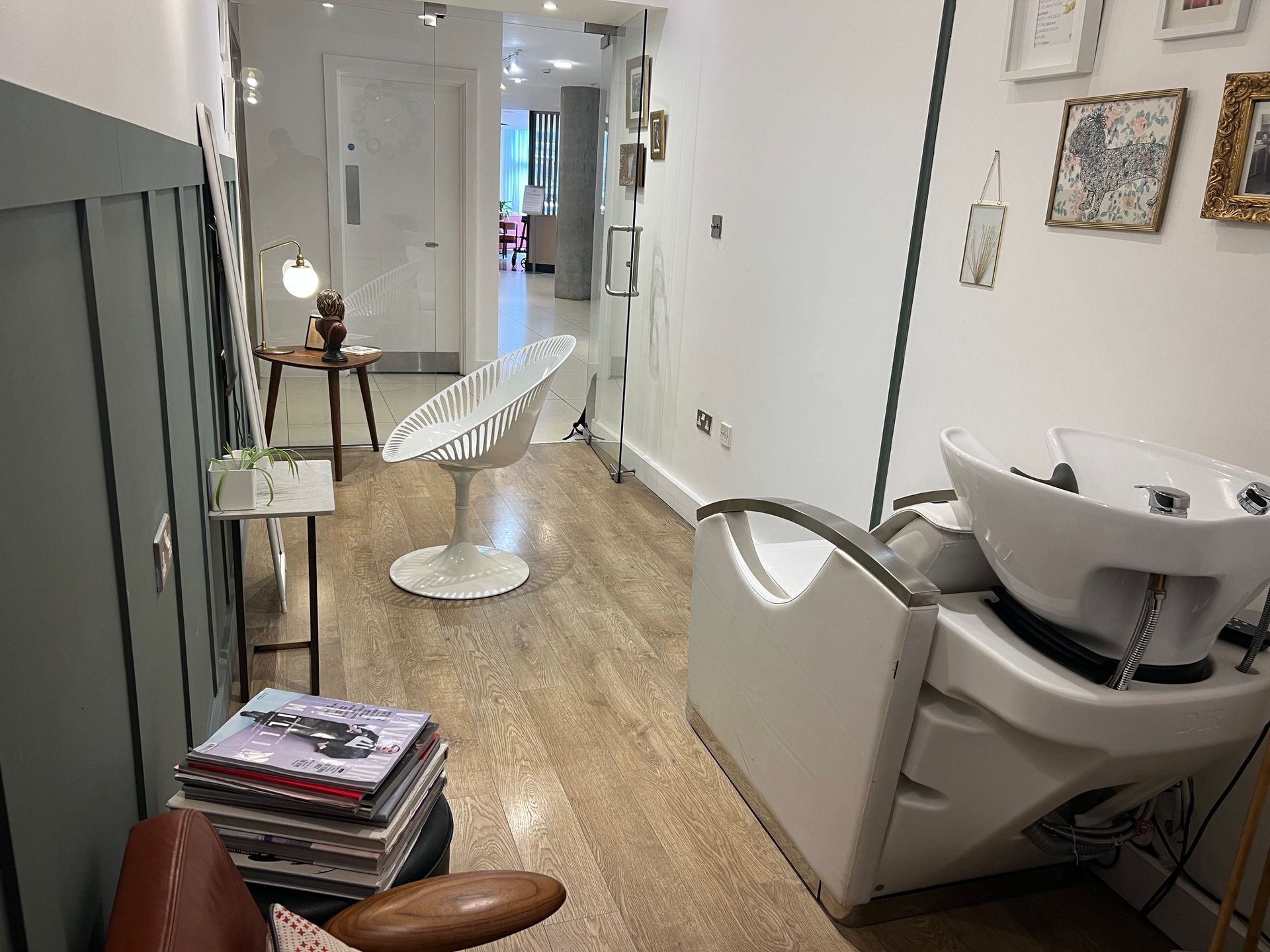 Hair salon interior with white and wood tones; includes a wash station and seating.