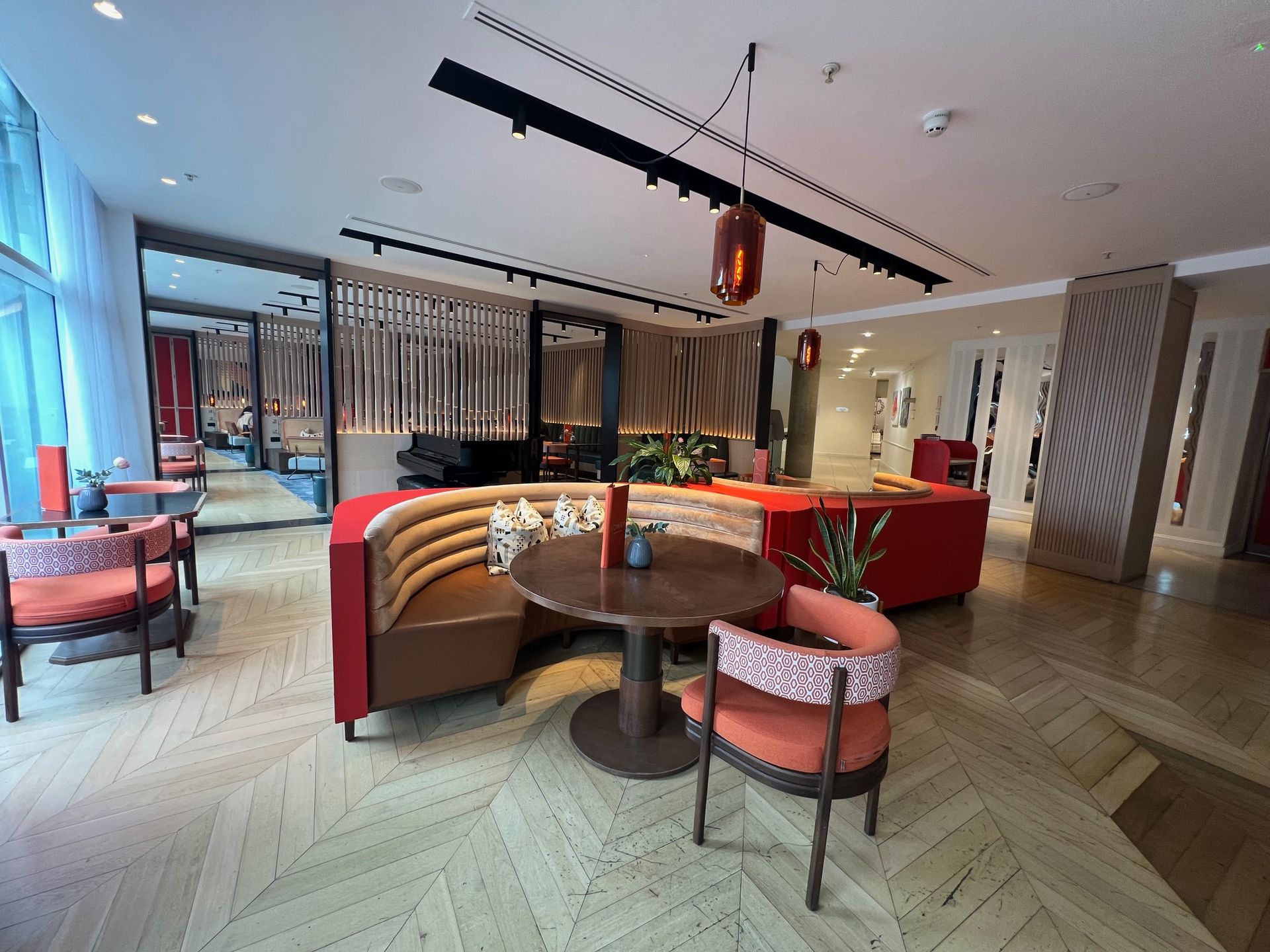 Modern lounge area with red and brown seating, wood floors, and a decorative partition.