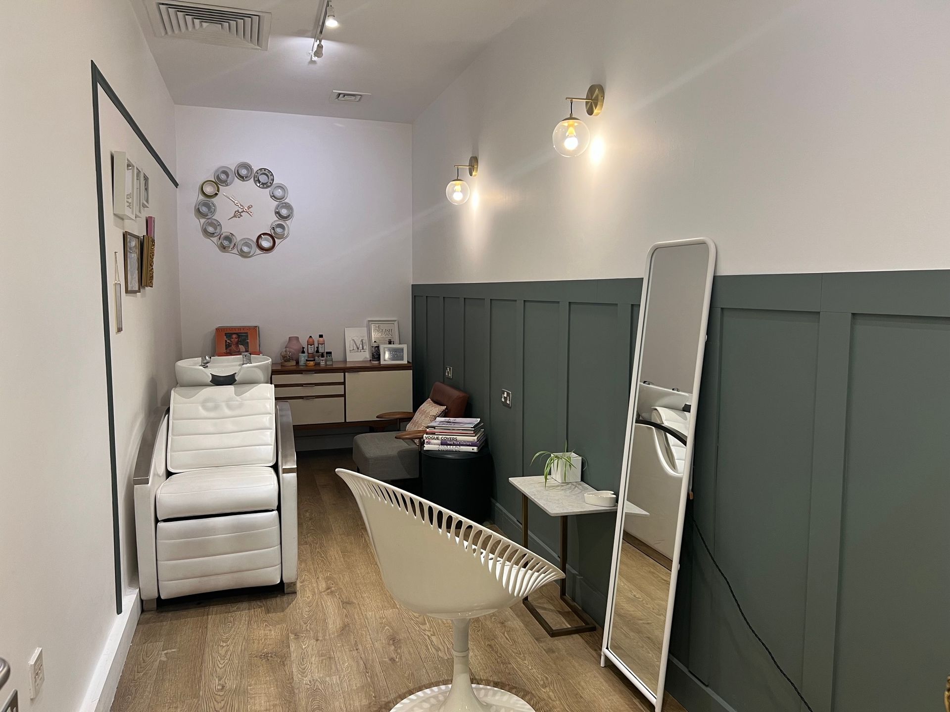 Hair salon interior with a wash station, mirror, and styling chair. White and green walls.