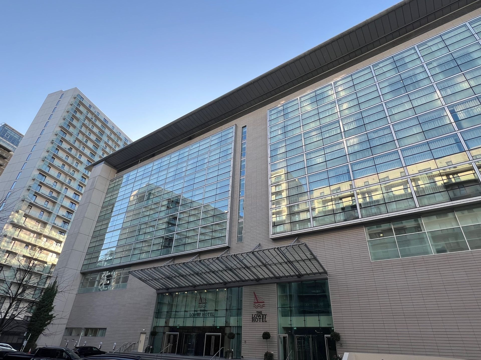 Modern building with glass windows, gray facade, and a taller building in the background.