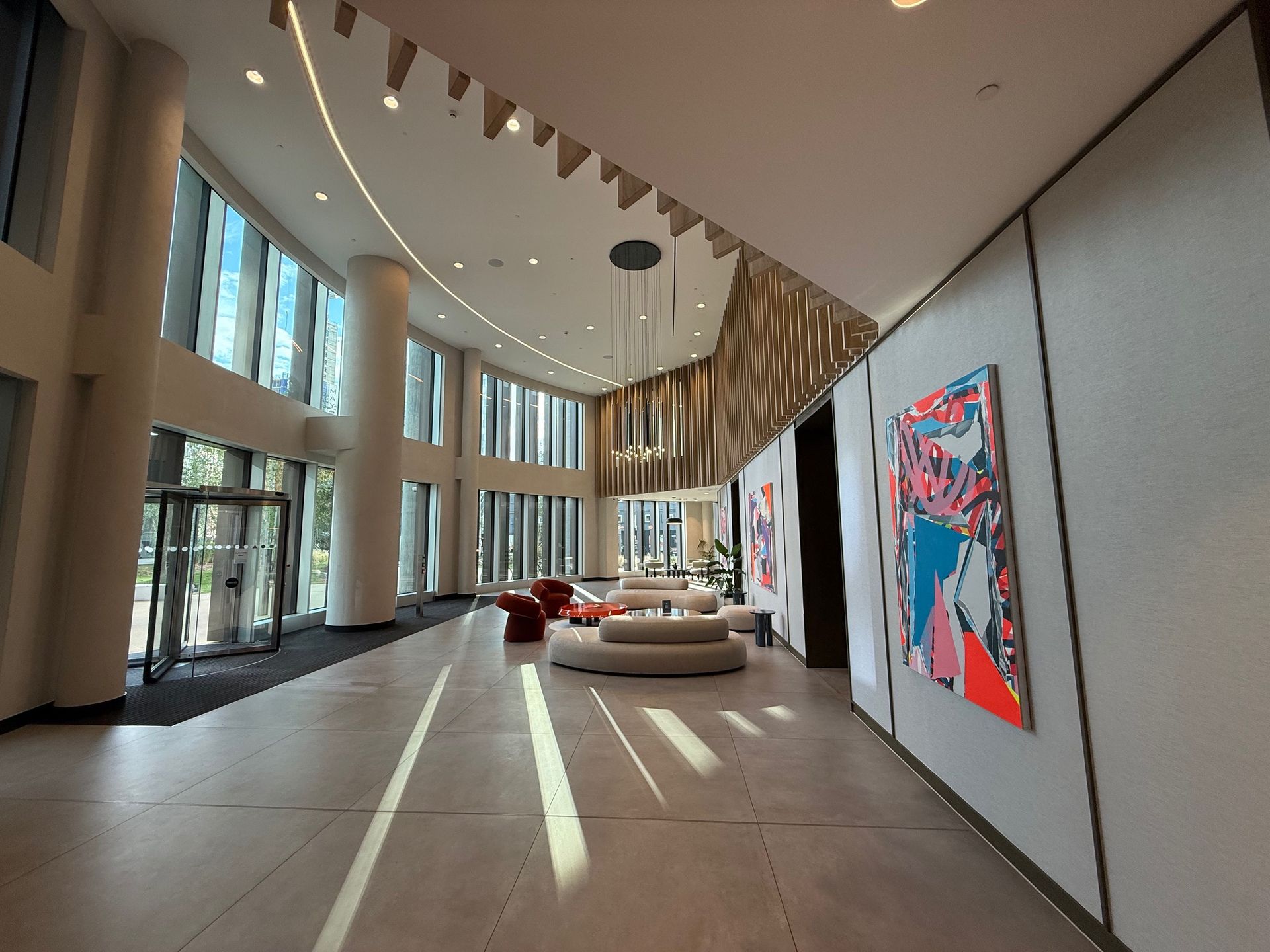 Lobby with large windows, modern furniture, artwork, and a geometric ceiling design.