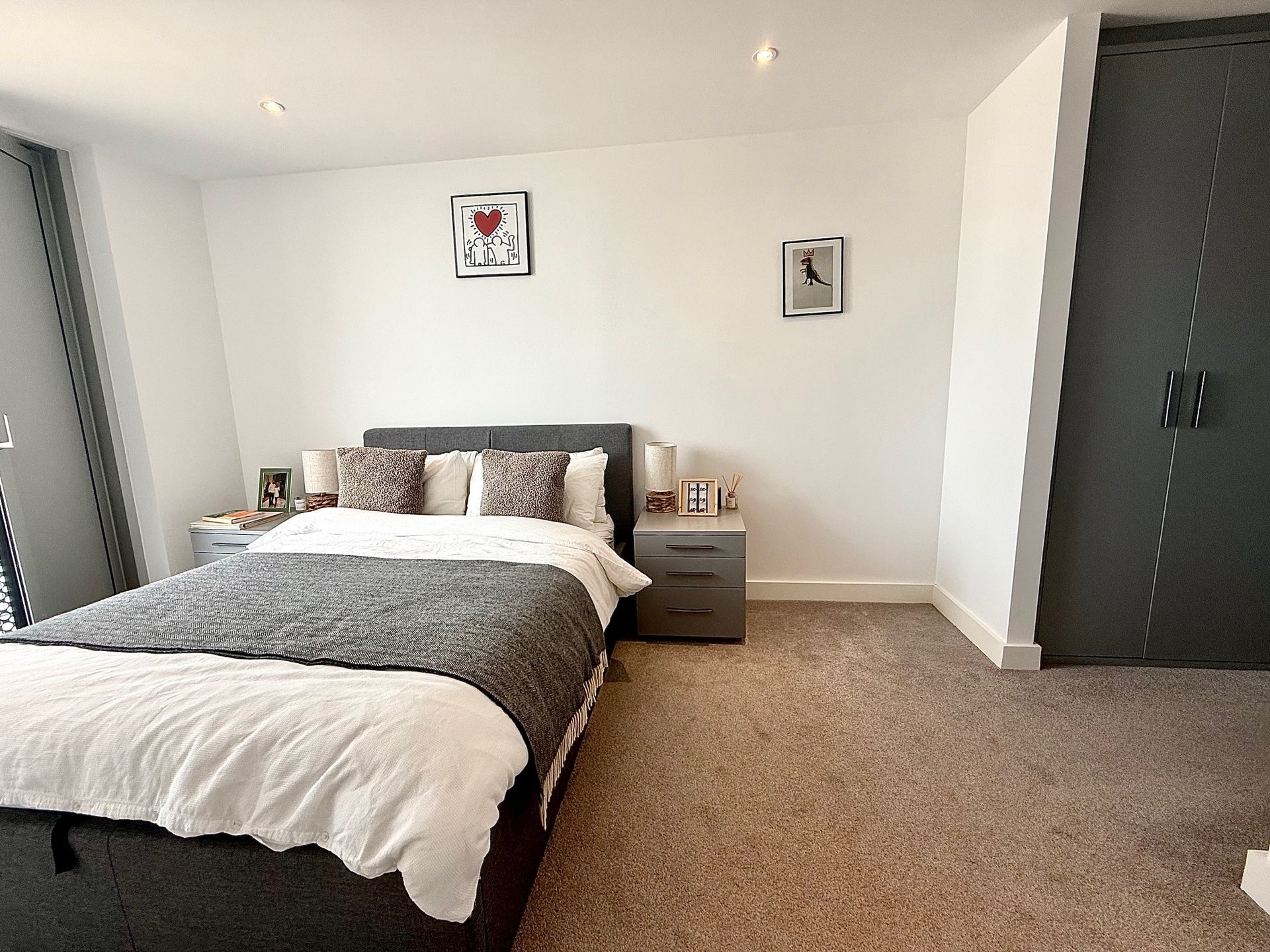 Bedroom with gray bed, nightstands, and closet; white walls, carpet.