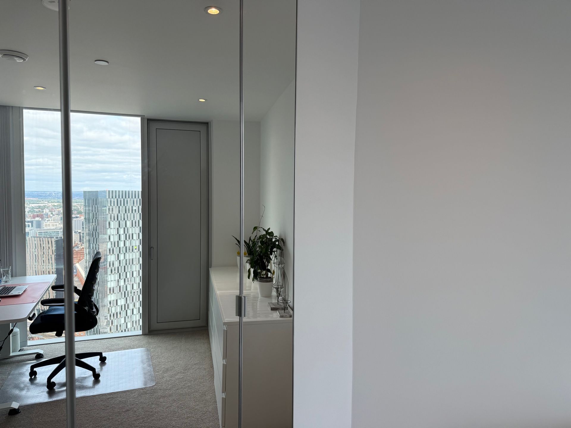 Office interior with desk, chair, window, and white cabinet.