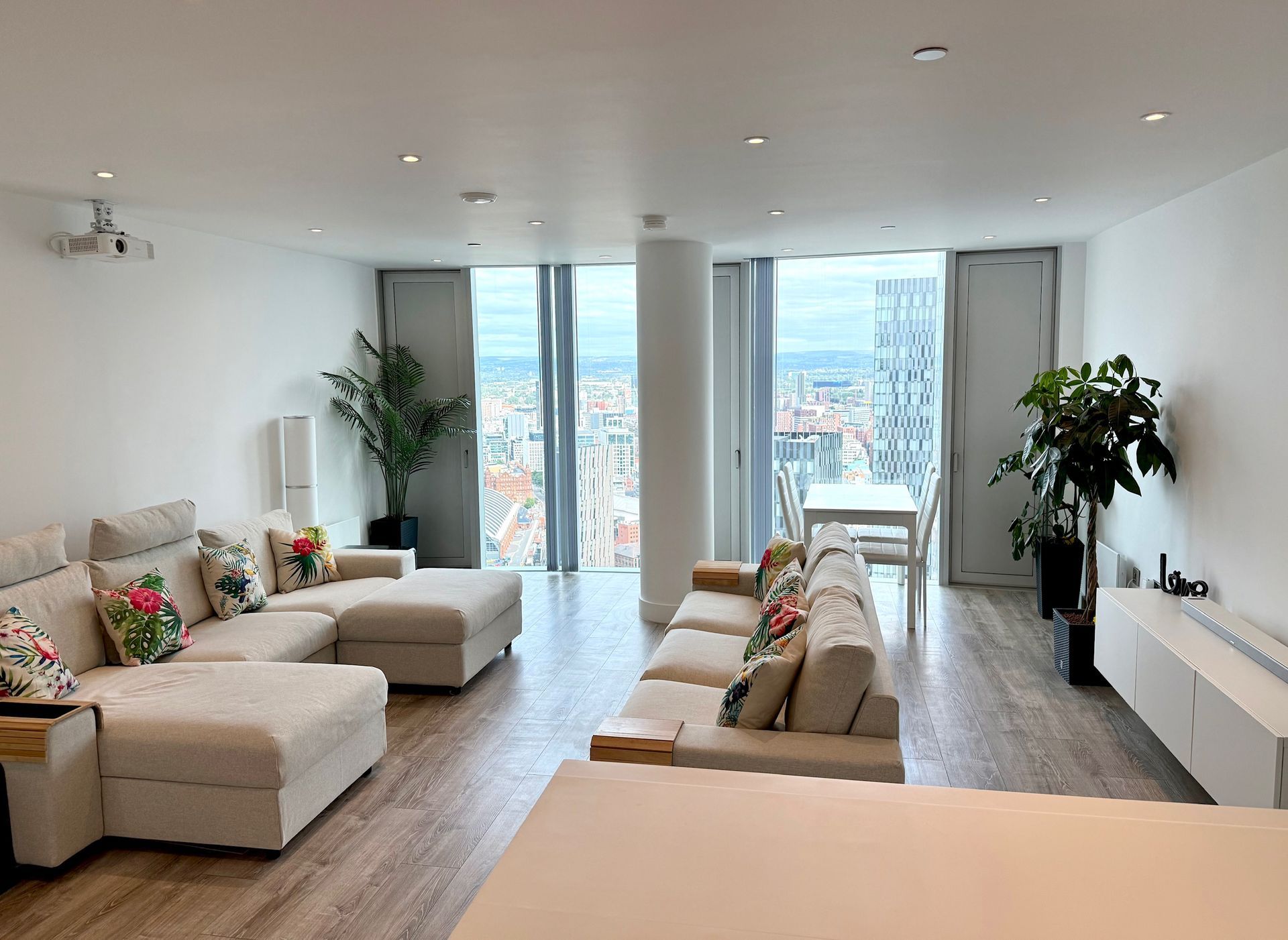 Spacious, light-filled living room with a large sectional, floor-to-ceiling windows, and city views.