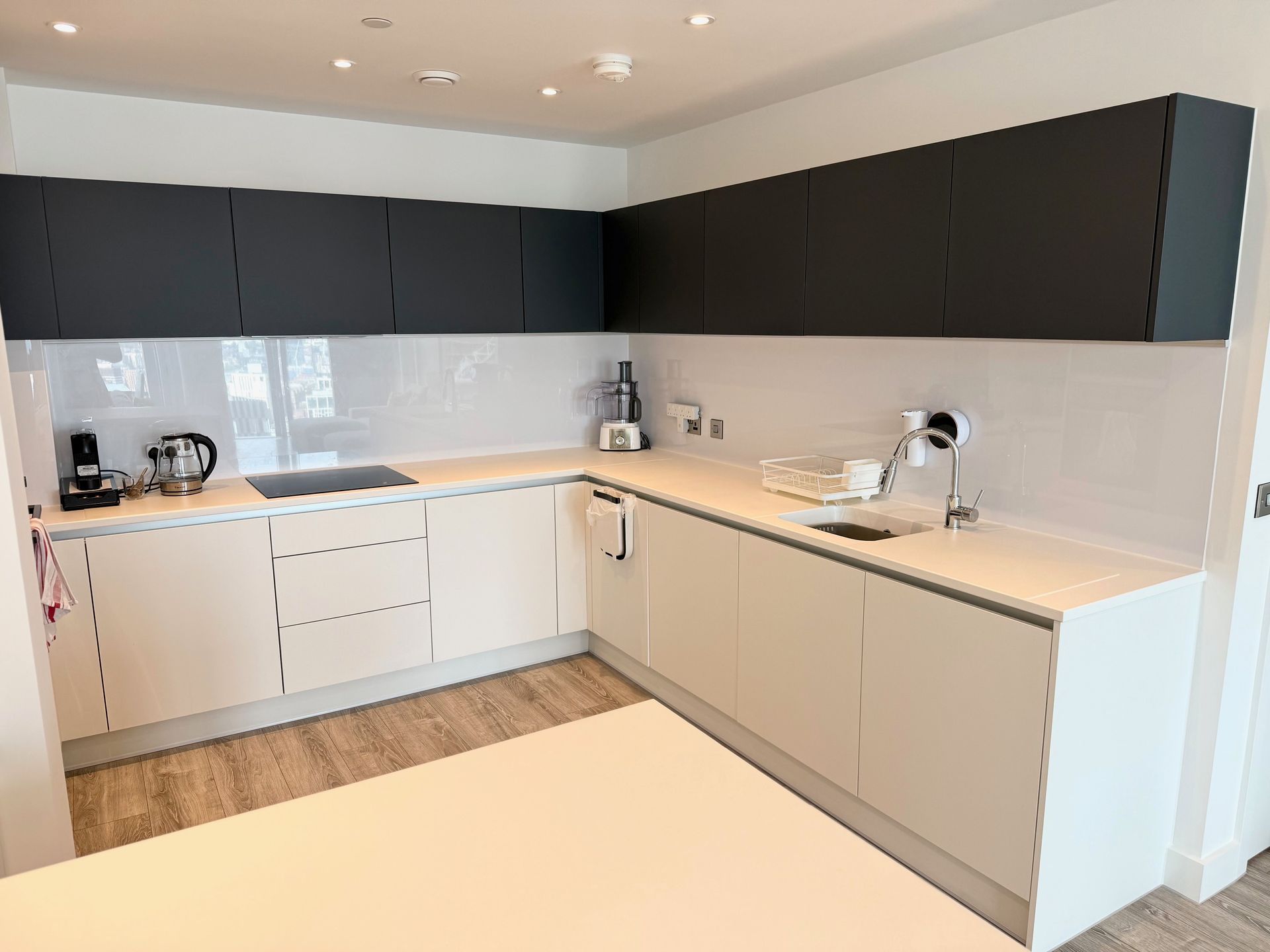 Modern kitchen with white lower cabinets, dark gray upper cabinets, and white backsplash.