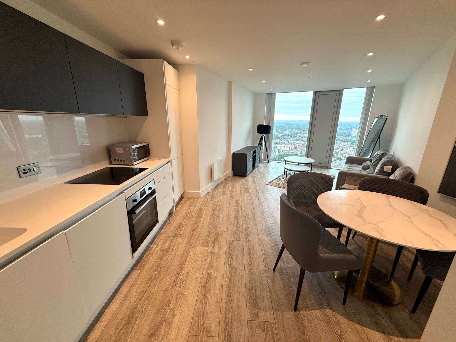 Modern apartment interior with kitchen, dining area, and living room featuring city views.