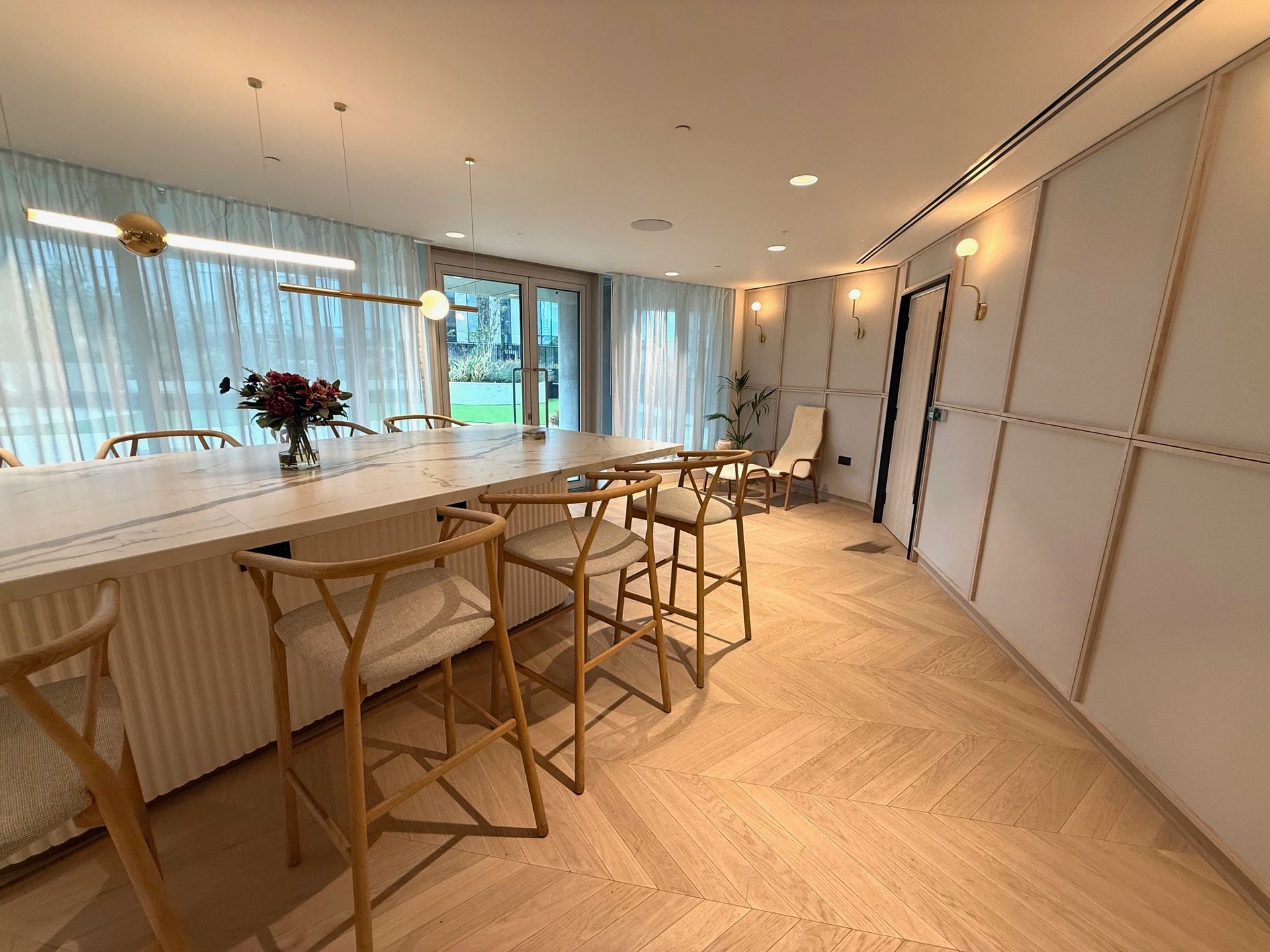 Modern kitchen with a long island, bar stools, and wooden floors.