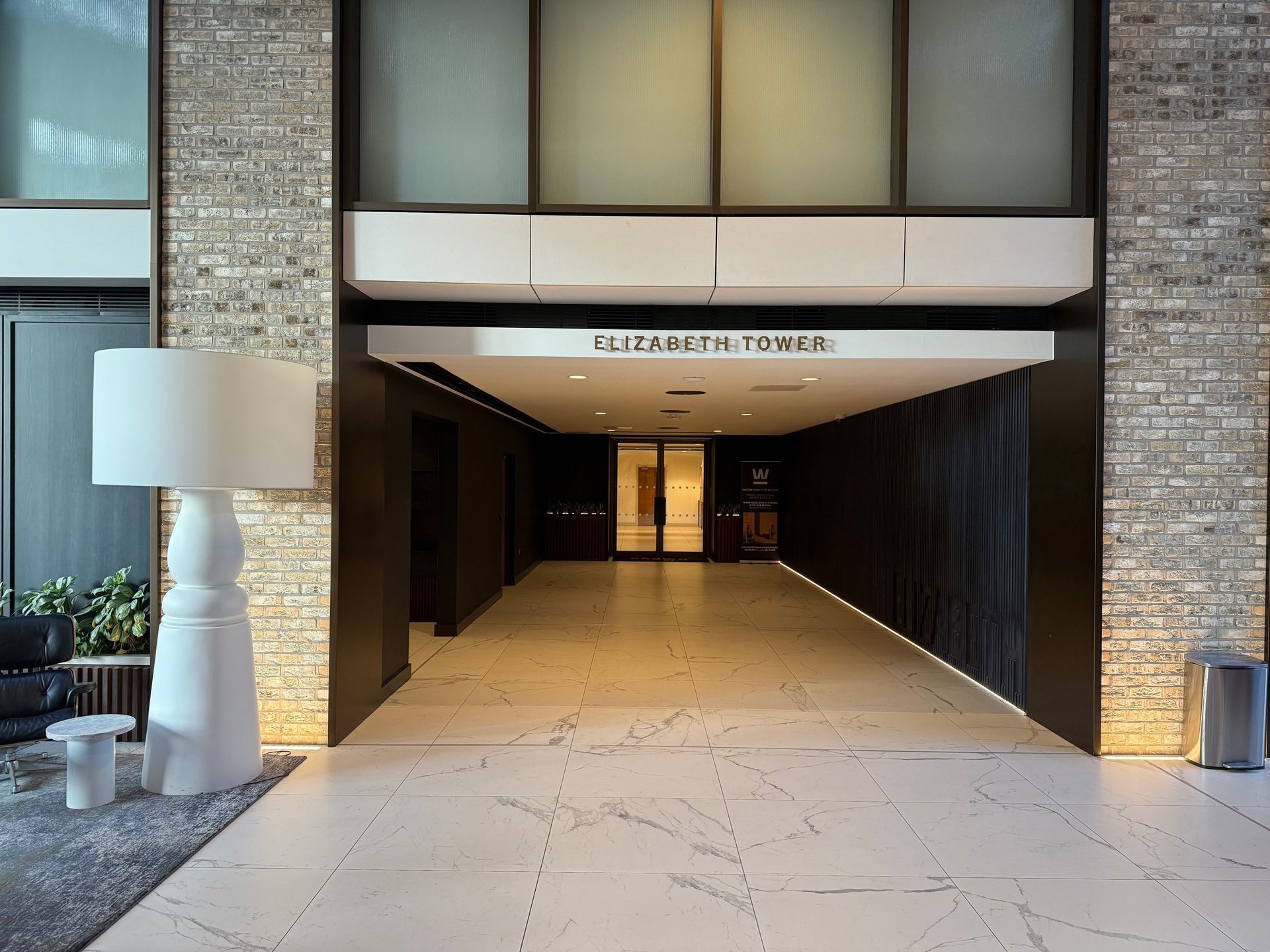 Lobby entrance with a white marble floor, a large lamp, and a sign reading