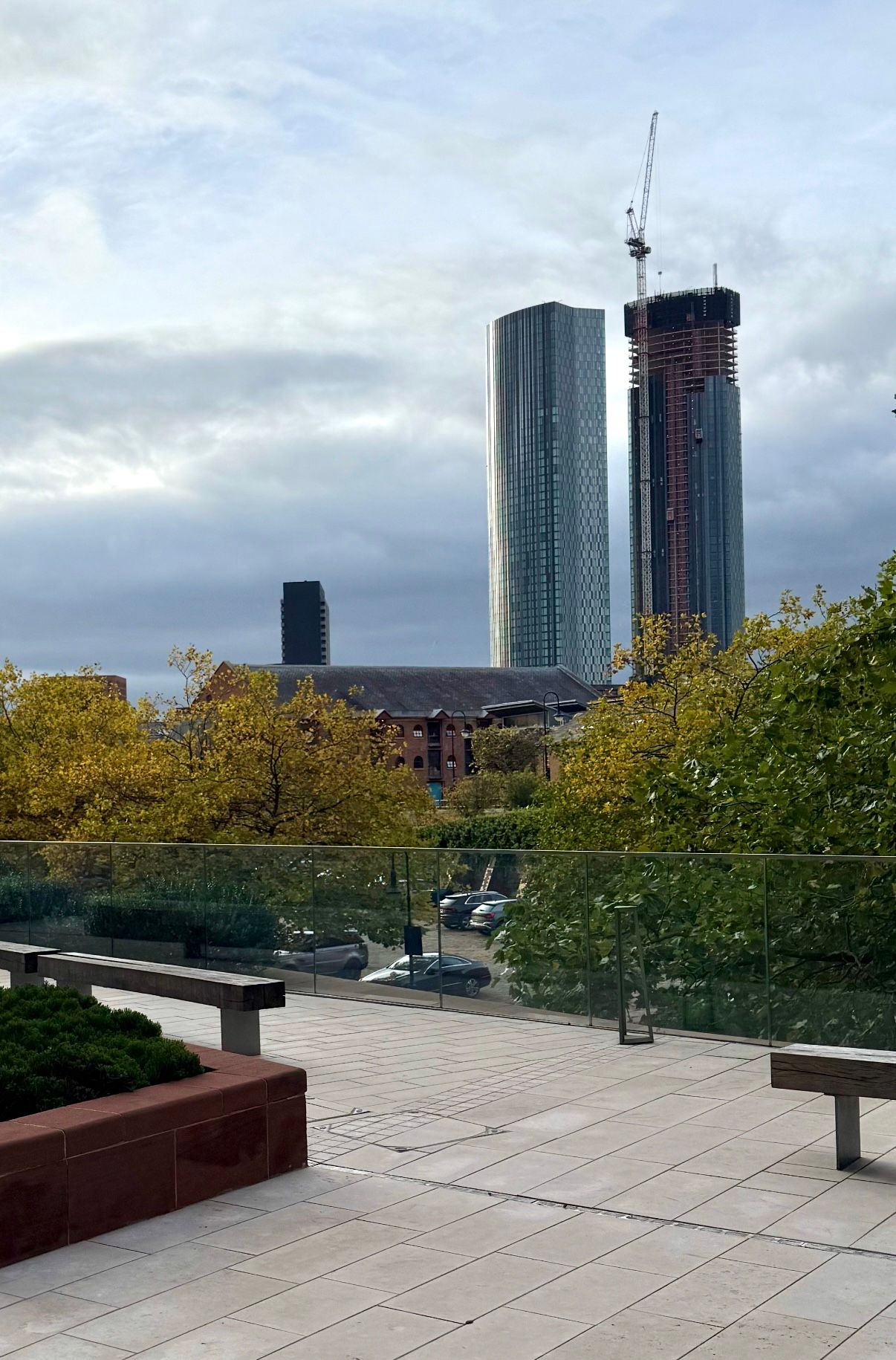 City skyline with two tall skyscrapers under construction, overcast sky.