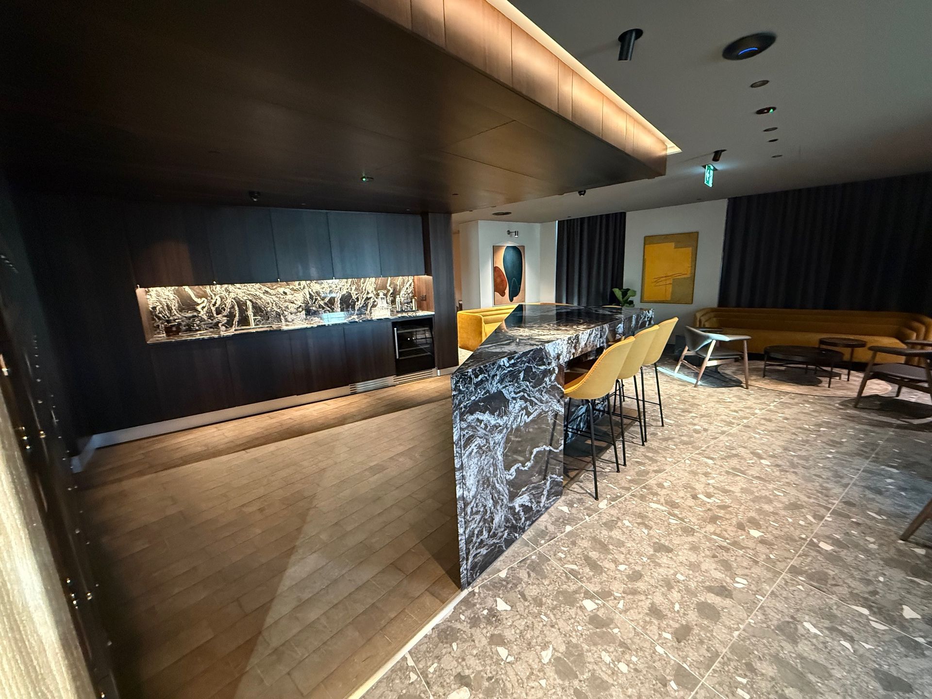 Luxurious interior with black marble bar, yellow chairs, art, and lounge area.