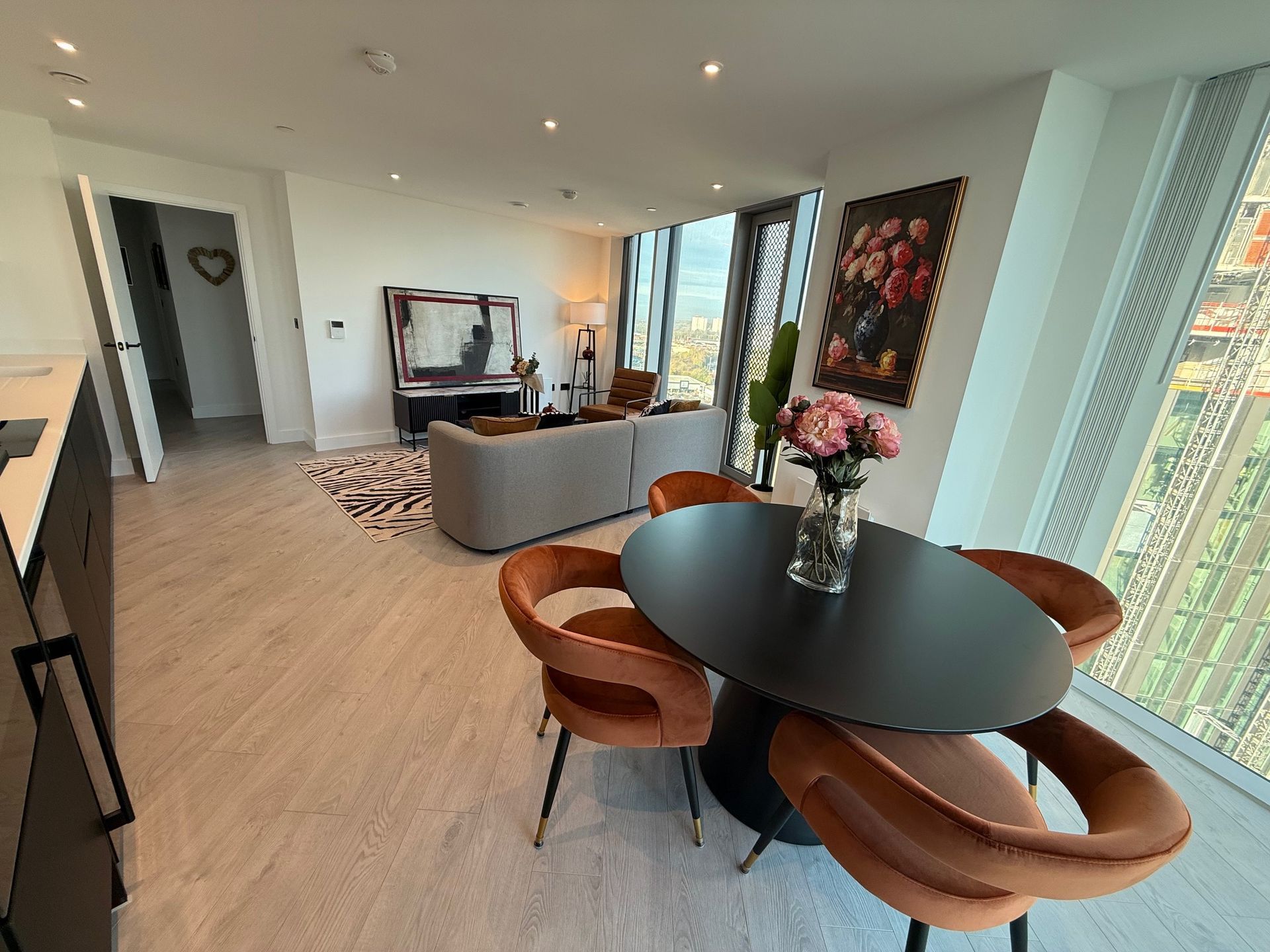 Modern apartment interior with a dining area, sofa, and city view.