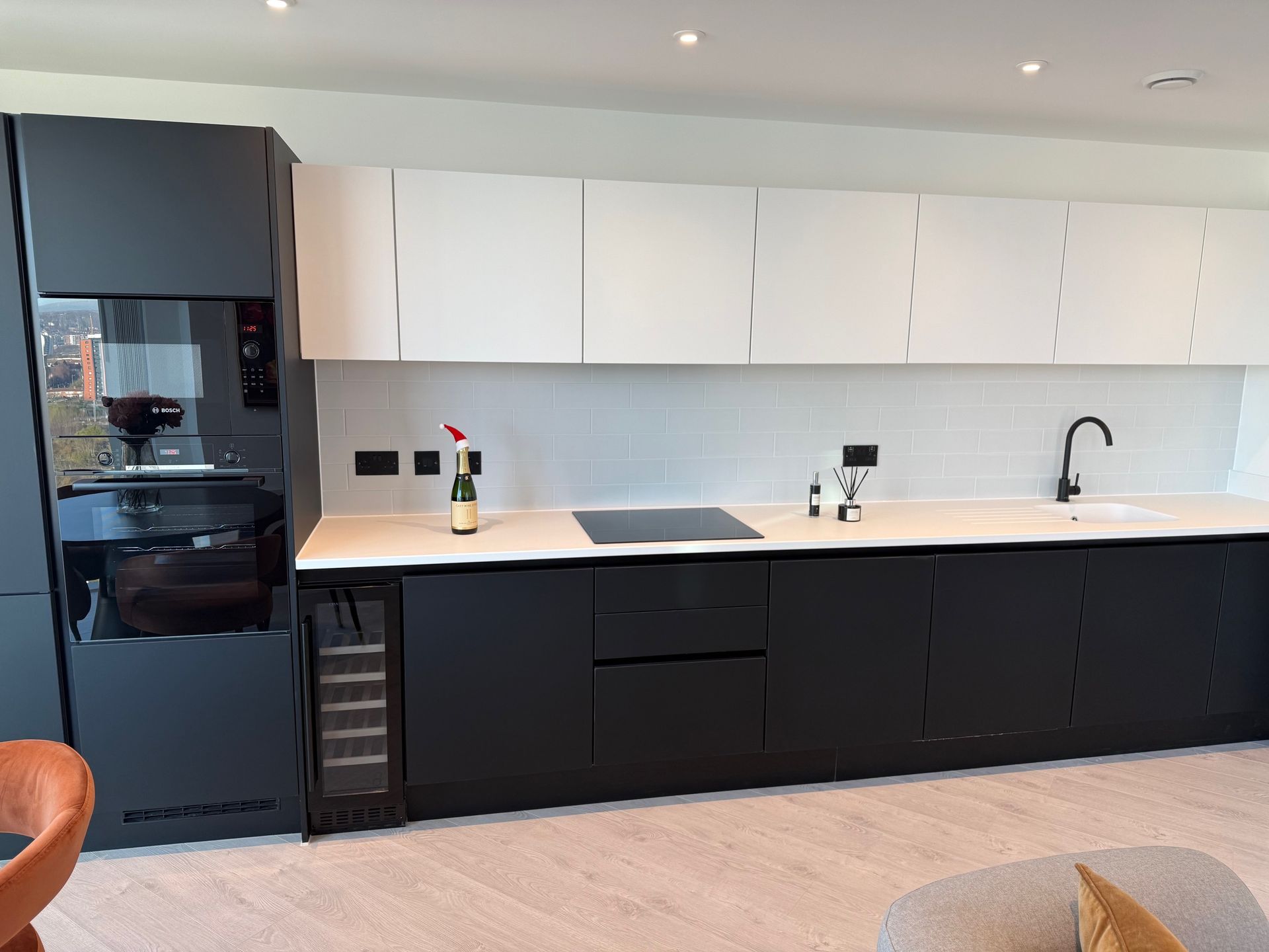 Modern kitchen with black and white cabinets, white countertop, and built-in appliances.