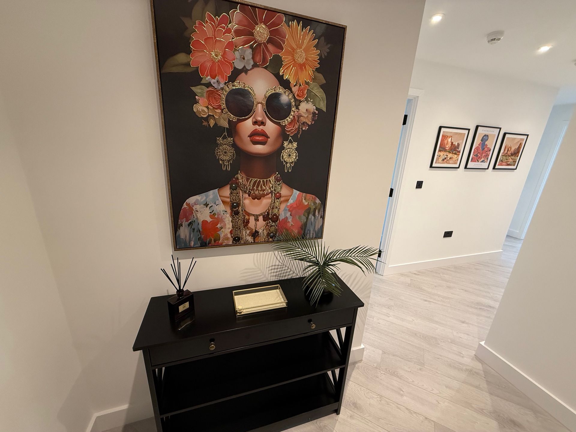 A hallway with a black console table under a large colorful portrait.