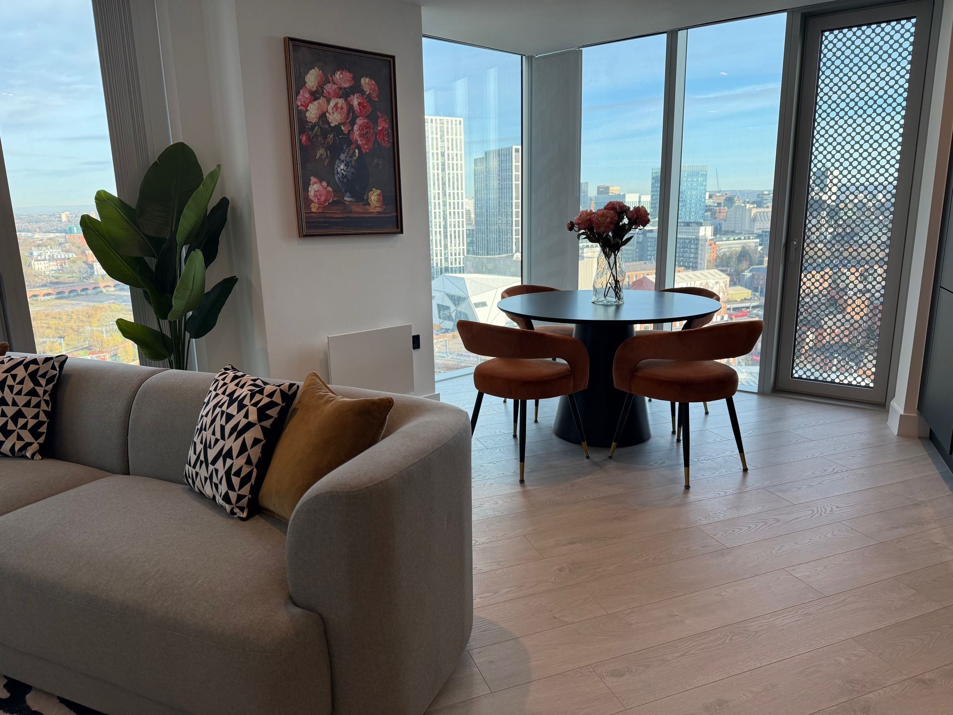 Modern apartment interior with a sofa, dining table, and city views.