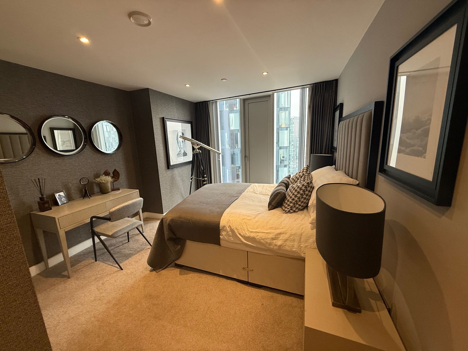 Bedroom with bed, vanity, mirrors, and door to balcony.