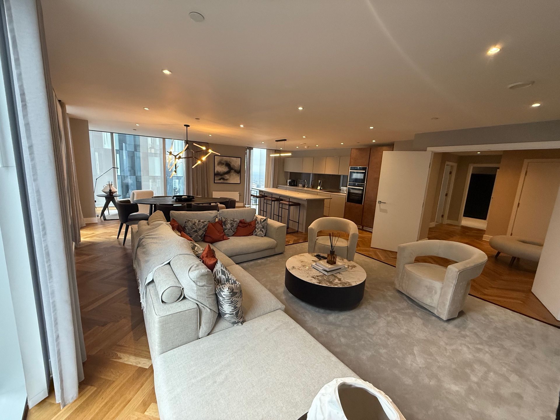 Modern living room with a large sofa, kitchen island, and dining area.