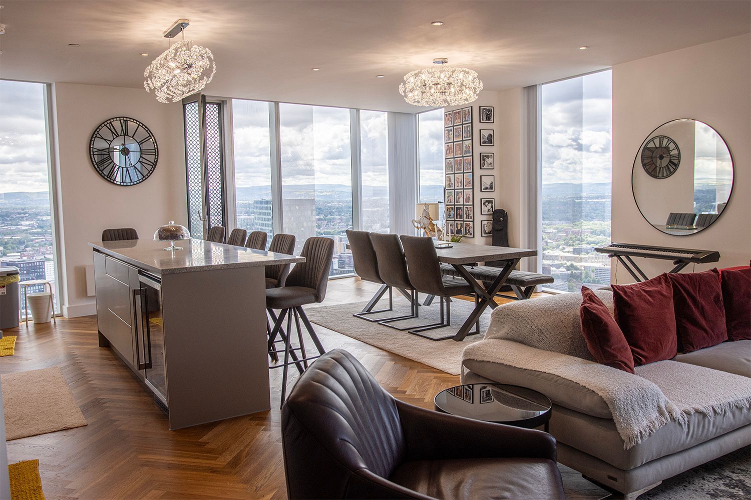 Spacious open-plan living area with cityscape views. Dining and kitchen areas feature a long island, table, and seating.