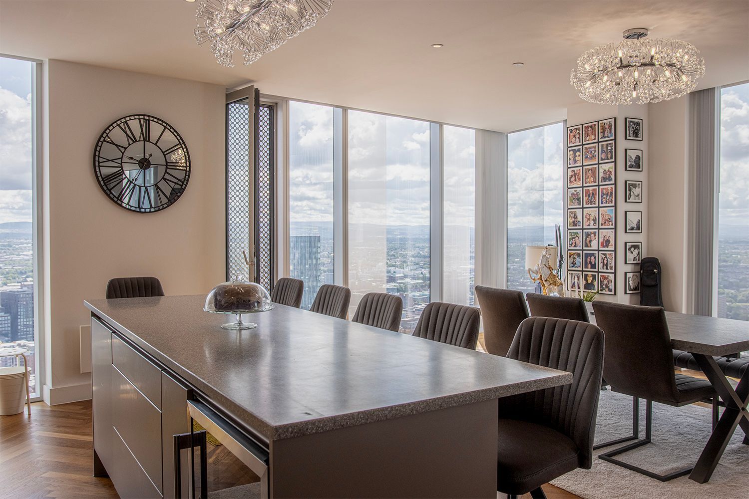 A modern dining room in a high-rise building with a large table, chairs, and expansive city views.