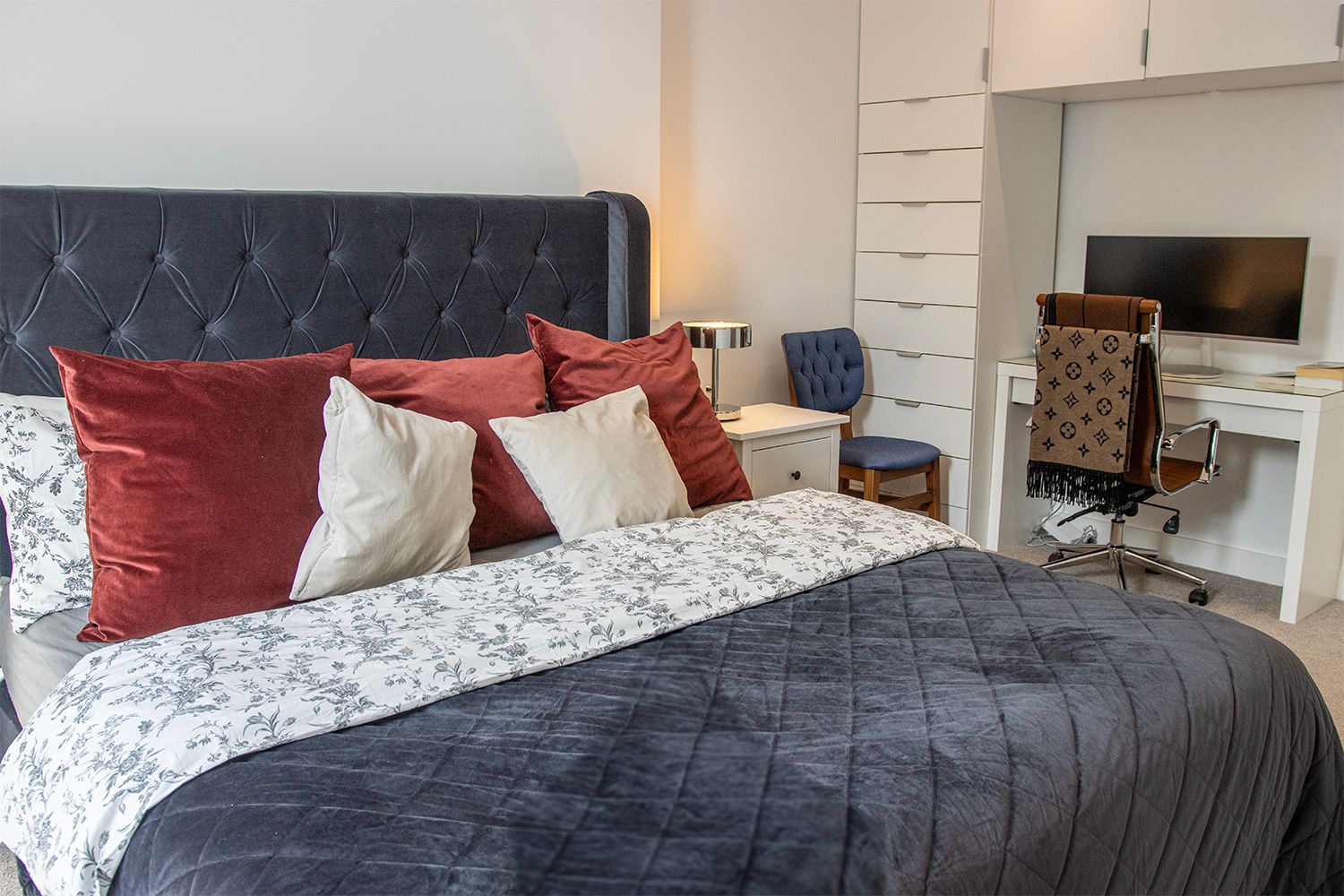 Bedroom with bed, desk, and built-in wardrobe; dark blue, red, and white color scheme.