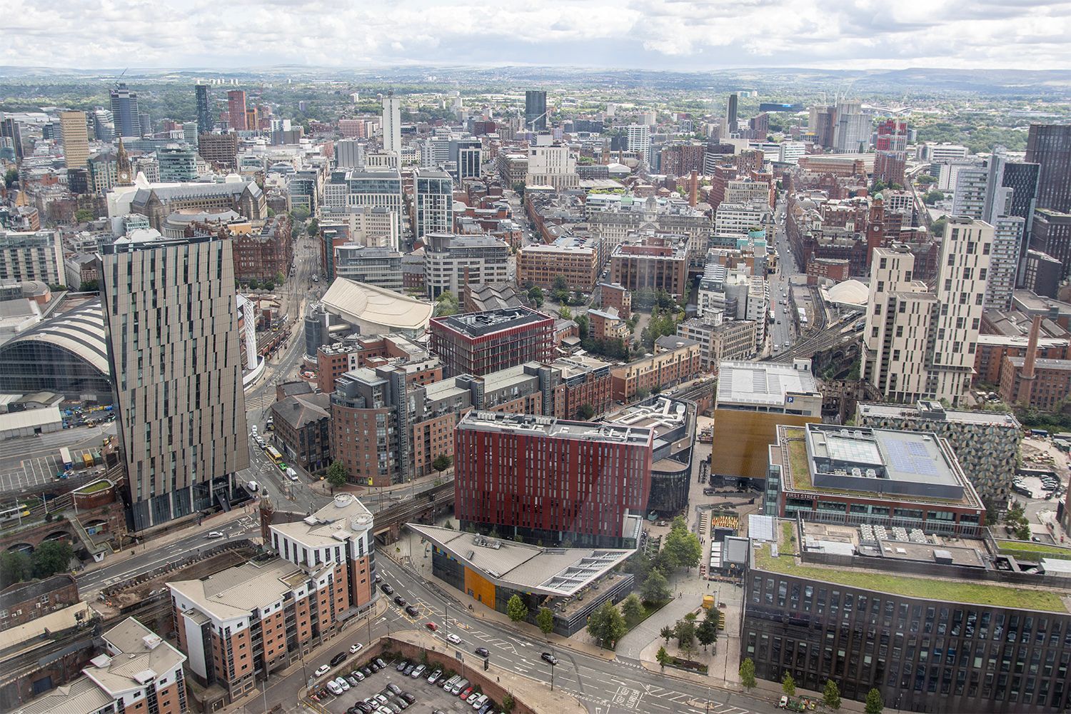 Aerial view of a city with many buildings, including skyscrapers, in various colors, on a cloudy day.