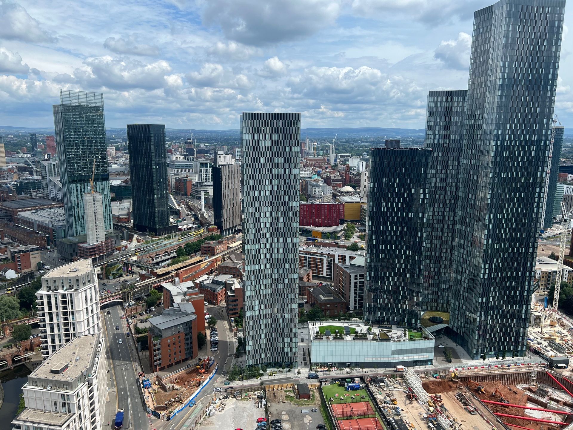 Cityscape featuring several tall skyscrapers under a partly cloudy sky.