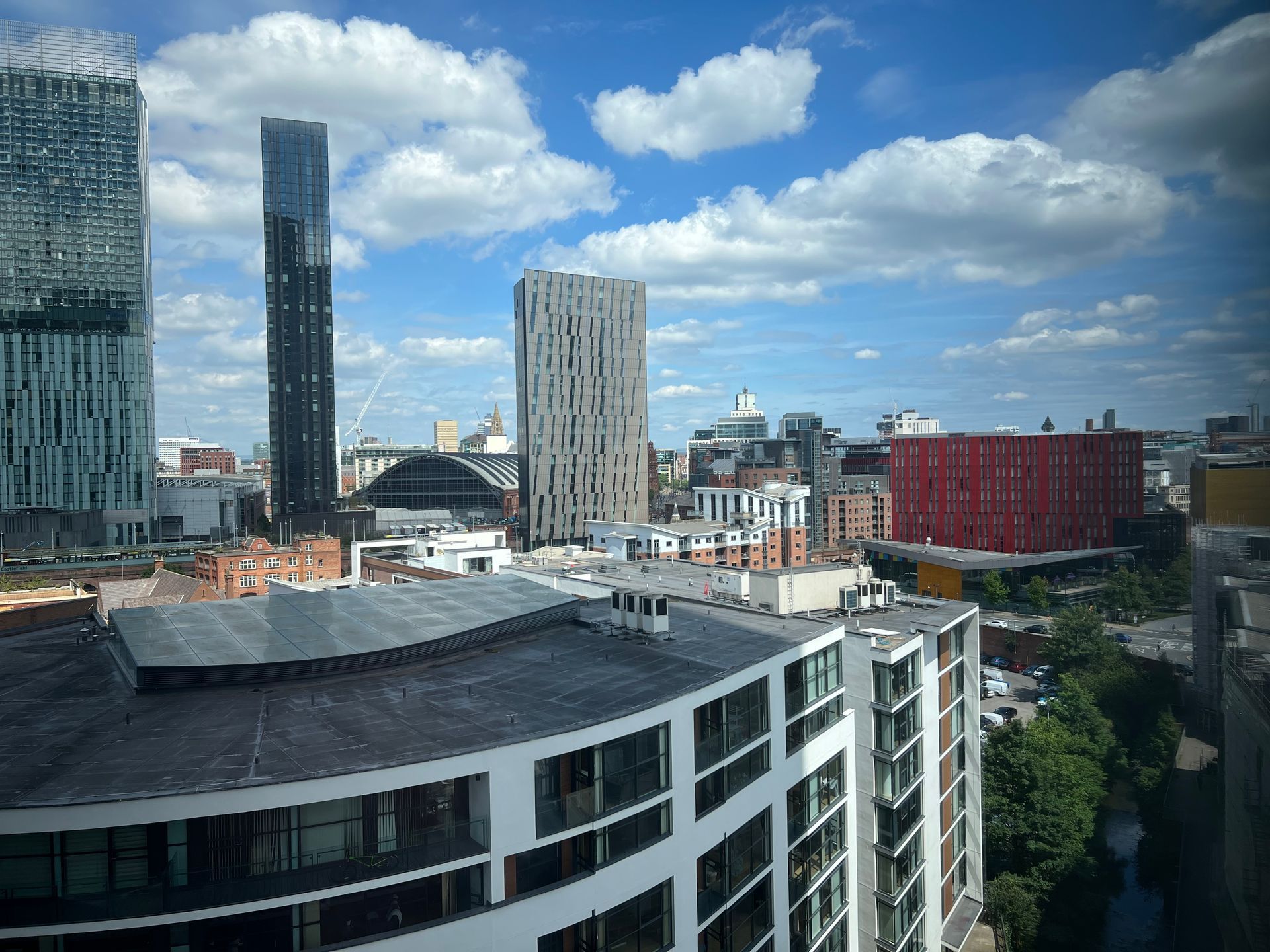 City skyline with skyscrapers under a blue sky with fluffy clouds.