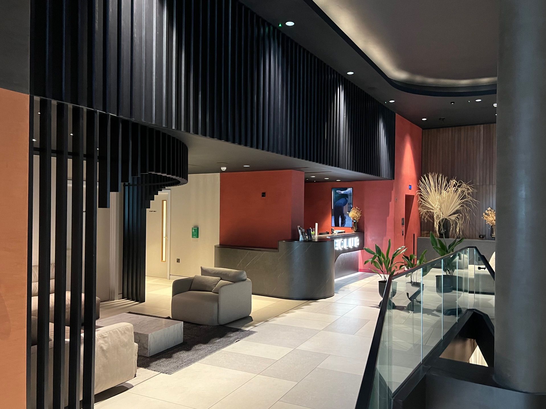 Lobby with modern design. Black slatted wall, peach and gray accents. Seating area and reception desk.