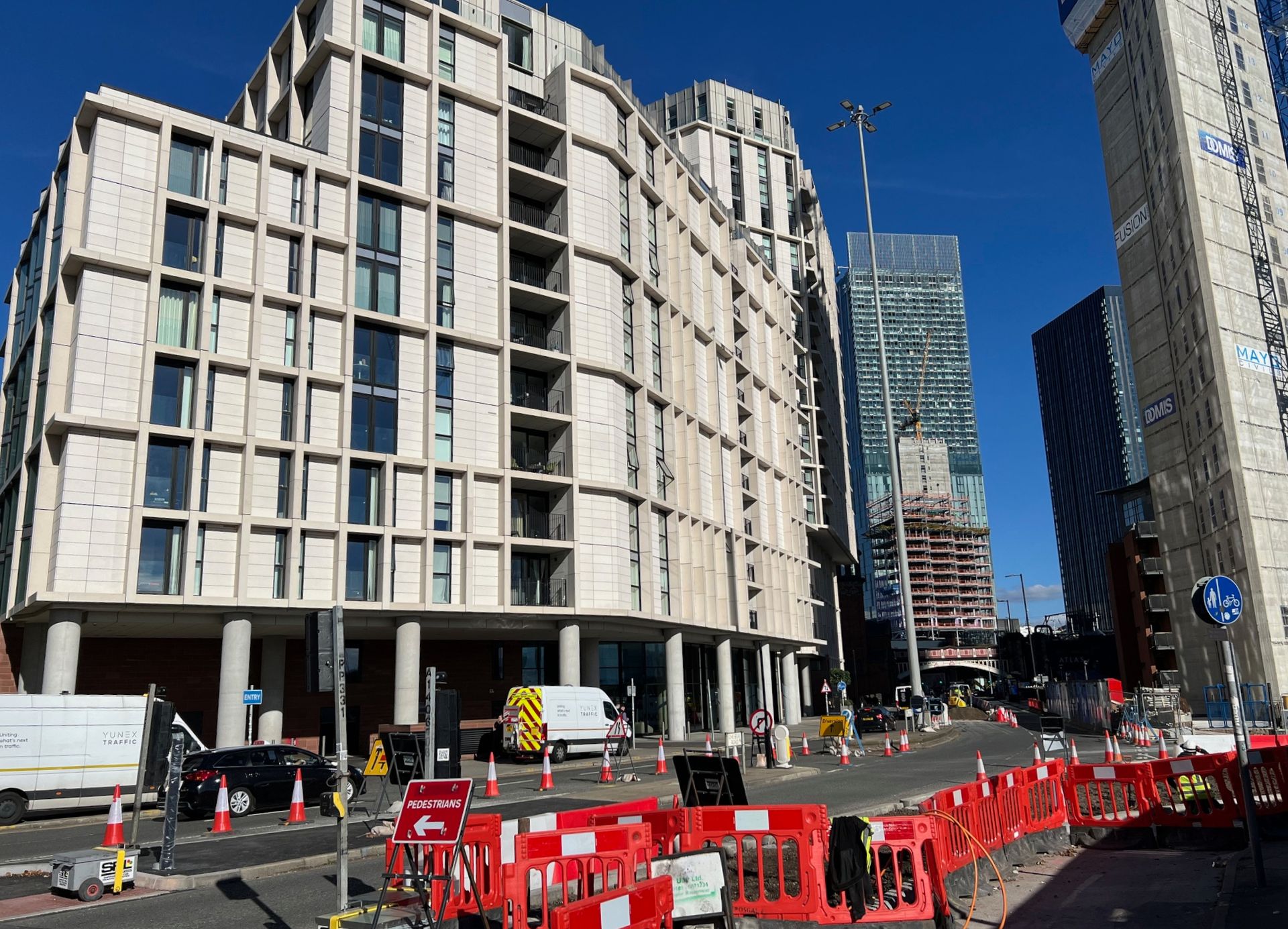 Buildings and construction site along a street under a clear, blue sky.