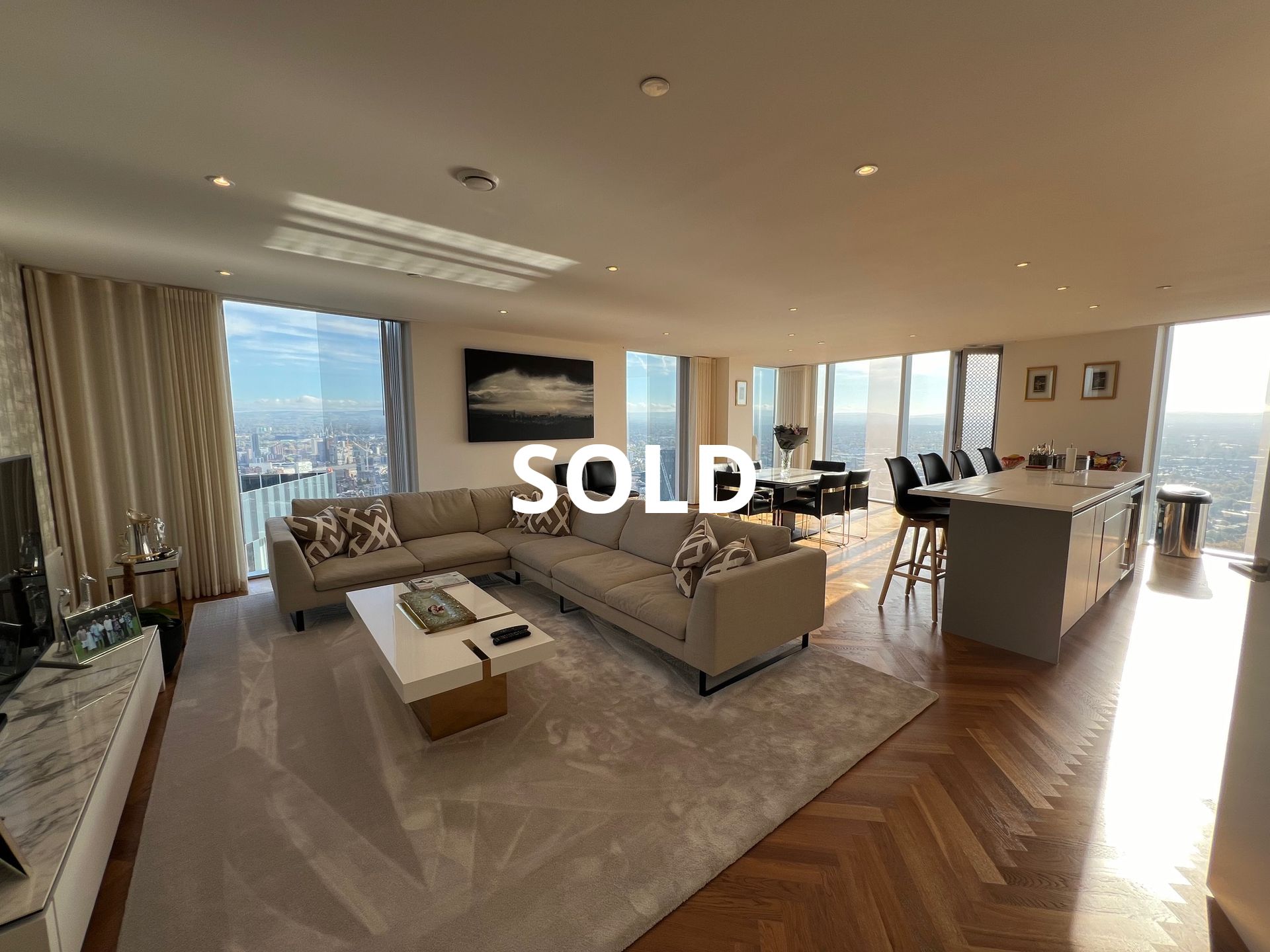Spacious, modern living room with floor-to-ceiling windows and city views. 