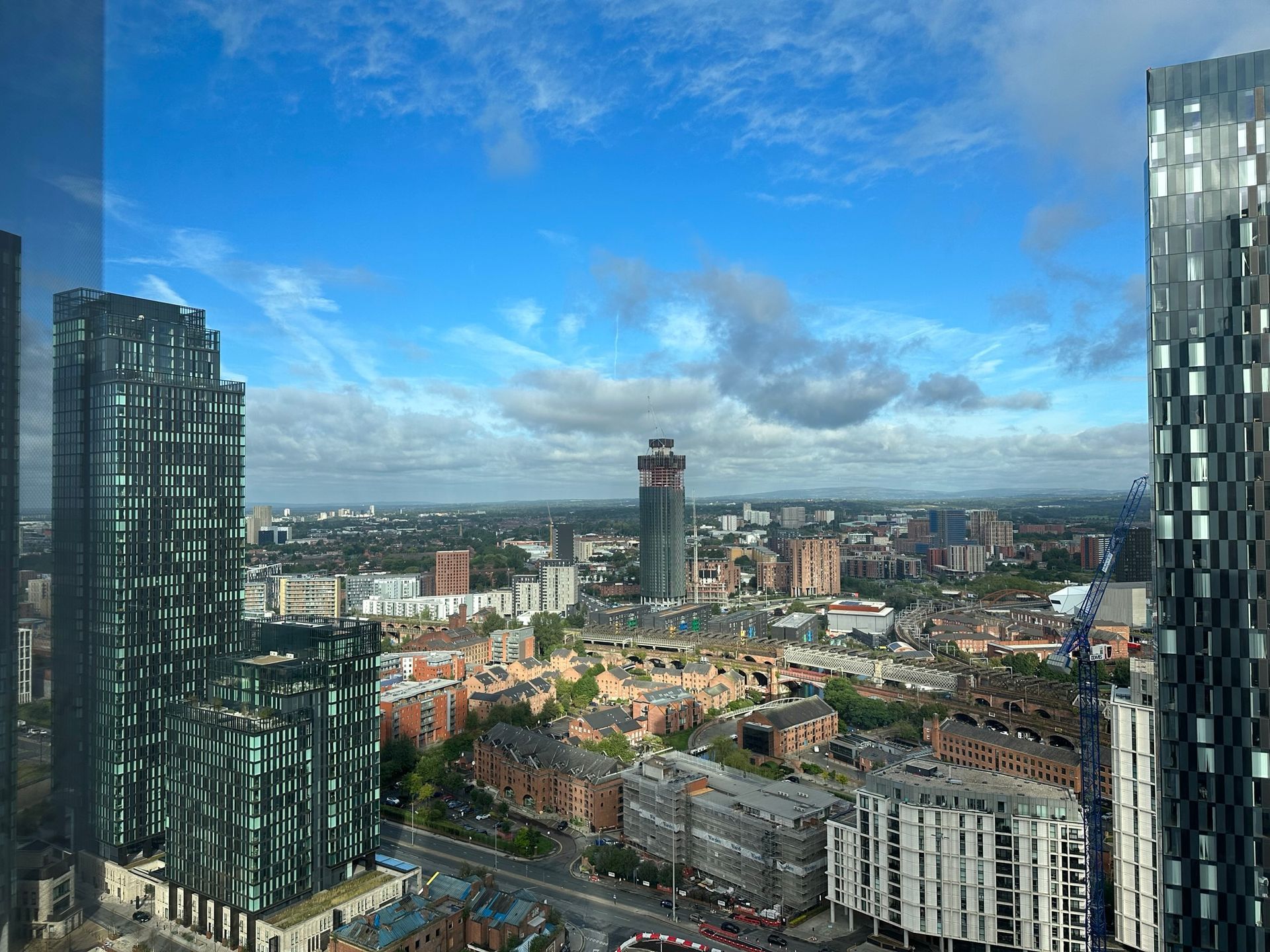 Cityscape with tall buildings under a blue sky with clouds.